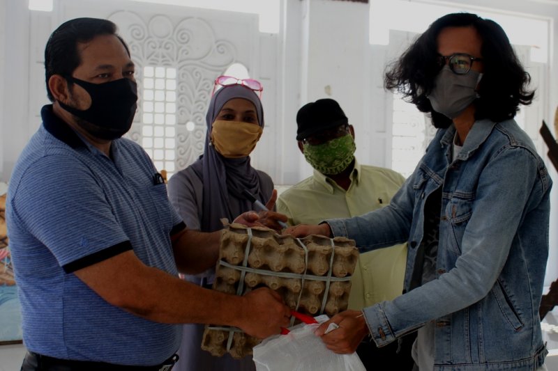 Kepala Dinas Pariwisata Banda Aceh Iskandar (kiri) menyerahkan paket sembako ke salah seorang pekerja seni di Gedung Rumoh Budaya.