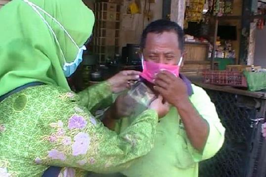 Seorang Kartini NU memakaikan masker pada seorang pedagang di Pasar Porong.