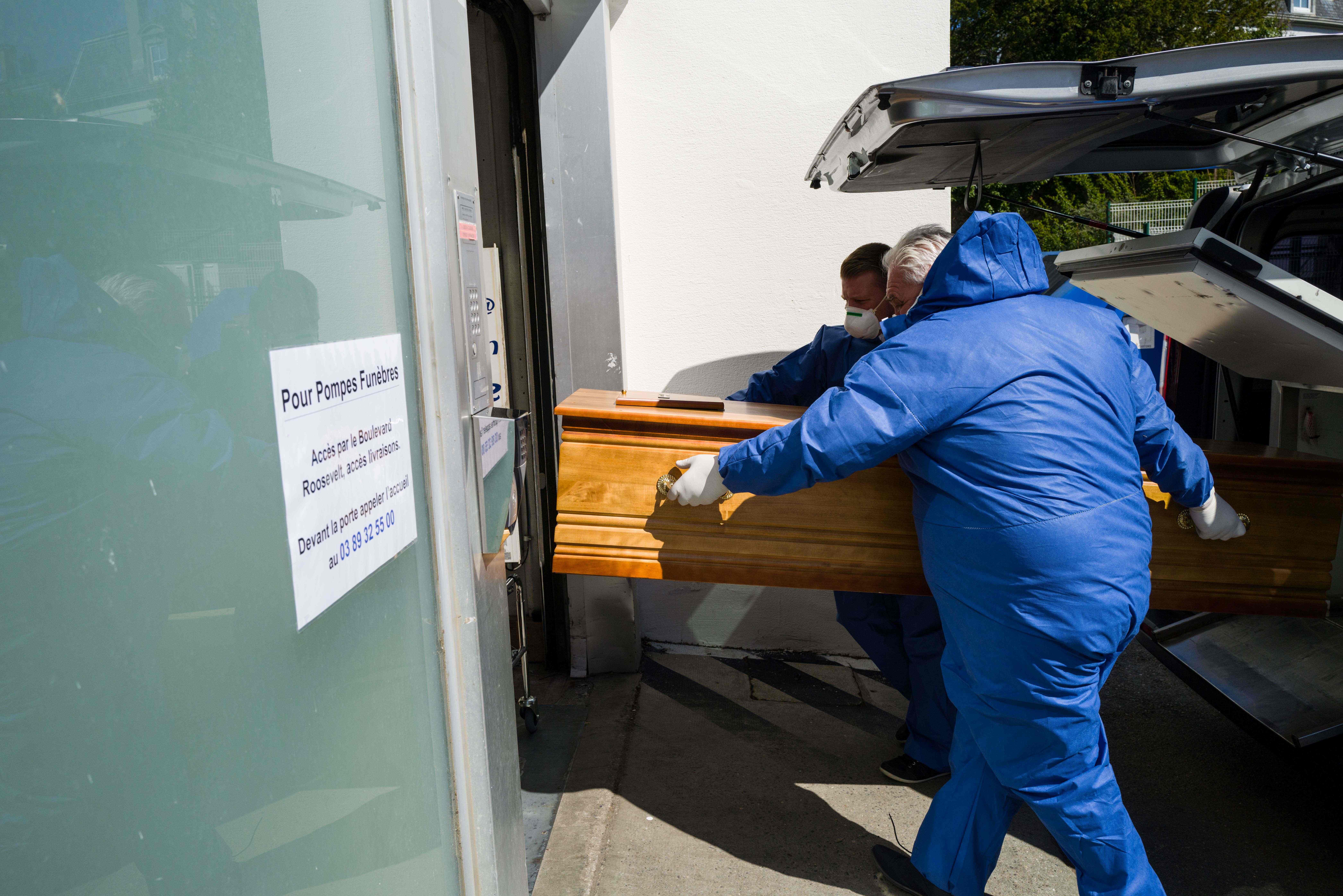 Pekerja rumah duka Lantz mengenakan masker dan pakaian pelindung memindahkan peti jenazah korban Covid-19 di Mulhouse, Prancis.