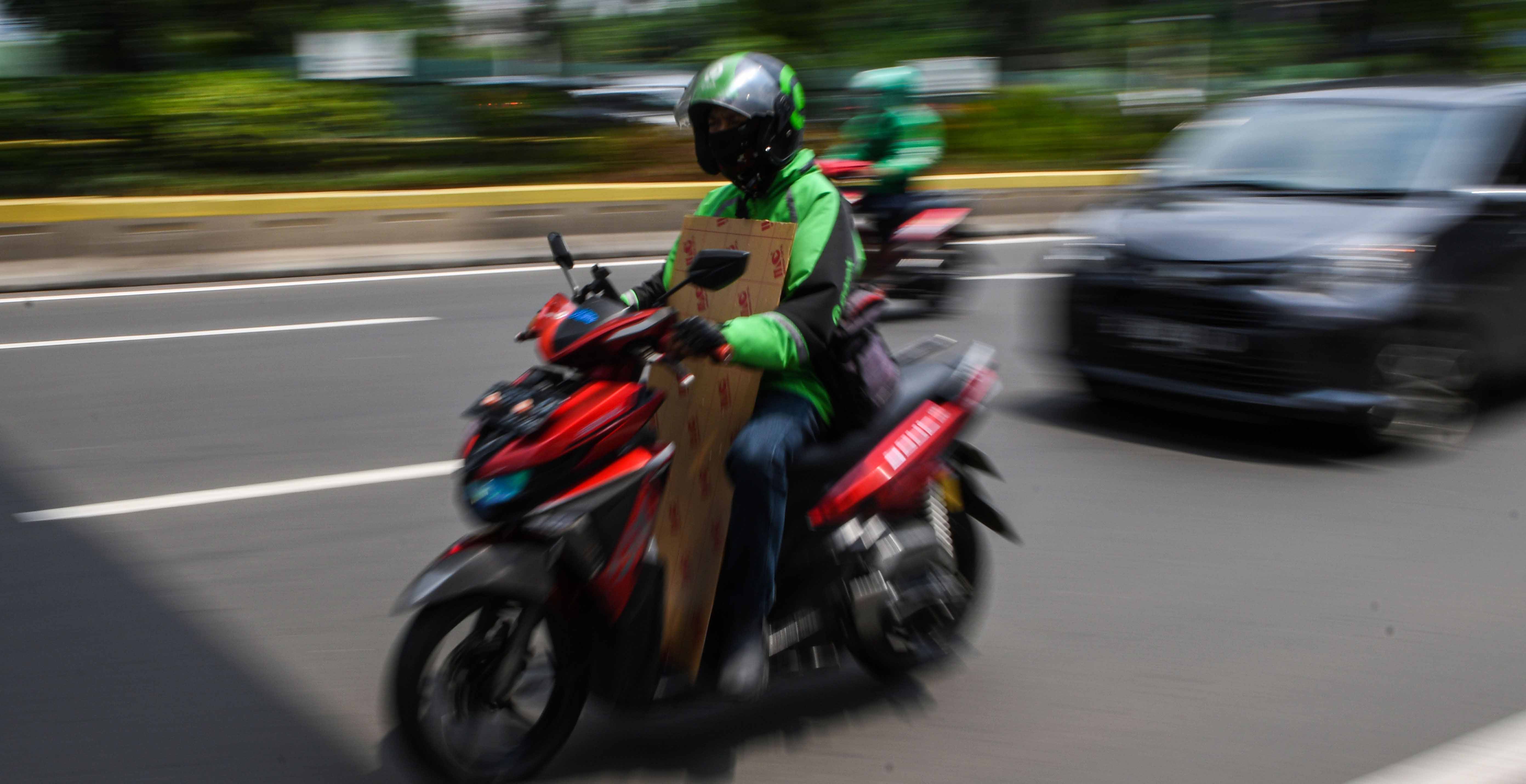  Pengemudi ojek daring membawa barang pesanan pelanggan saat melintas di kawasan Kramat Raya, Jakarta, Senin (13/4/2020). 
