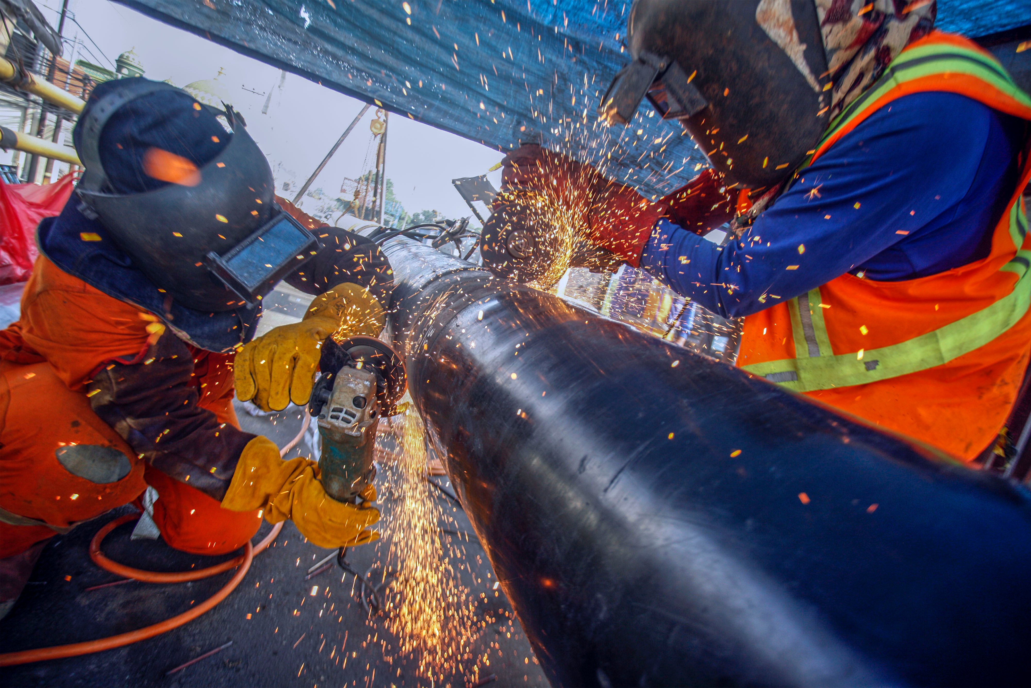 Pekerja sedang mengerjakan pipa jaringan gas.