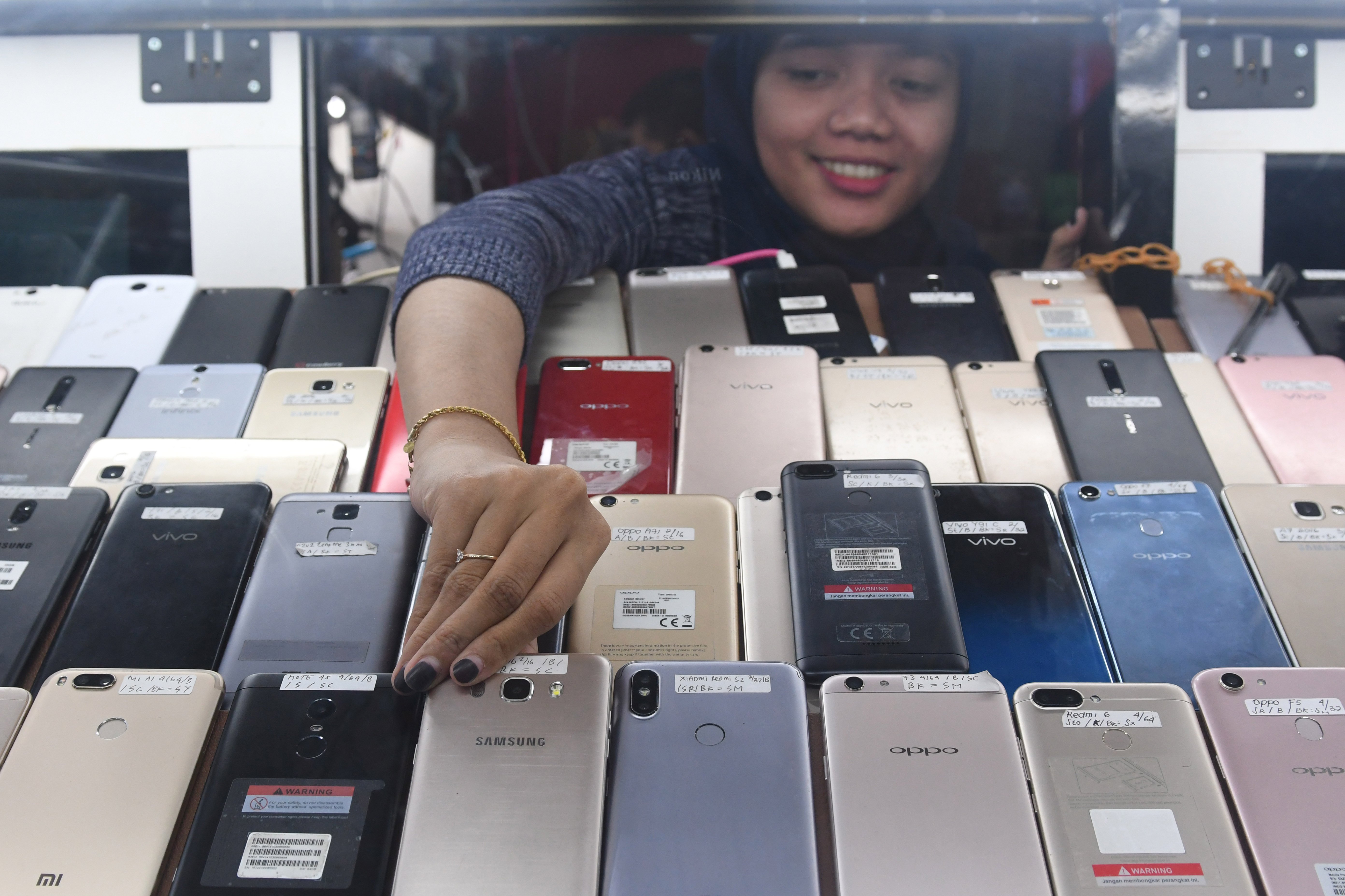 Pedagang mengambil salah satu ponsel di salah satu gerai di ITC Roxy Mas, Jakarta, Kamis (23/1/2020).