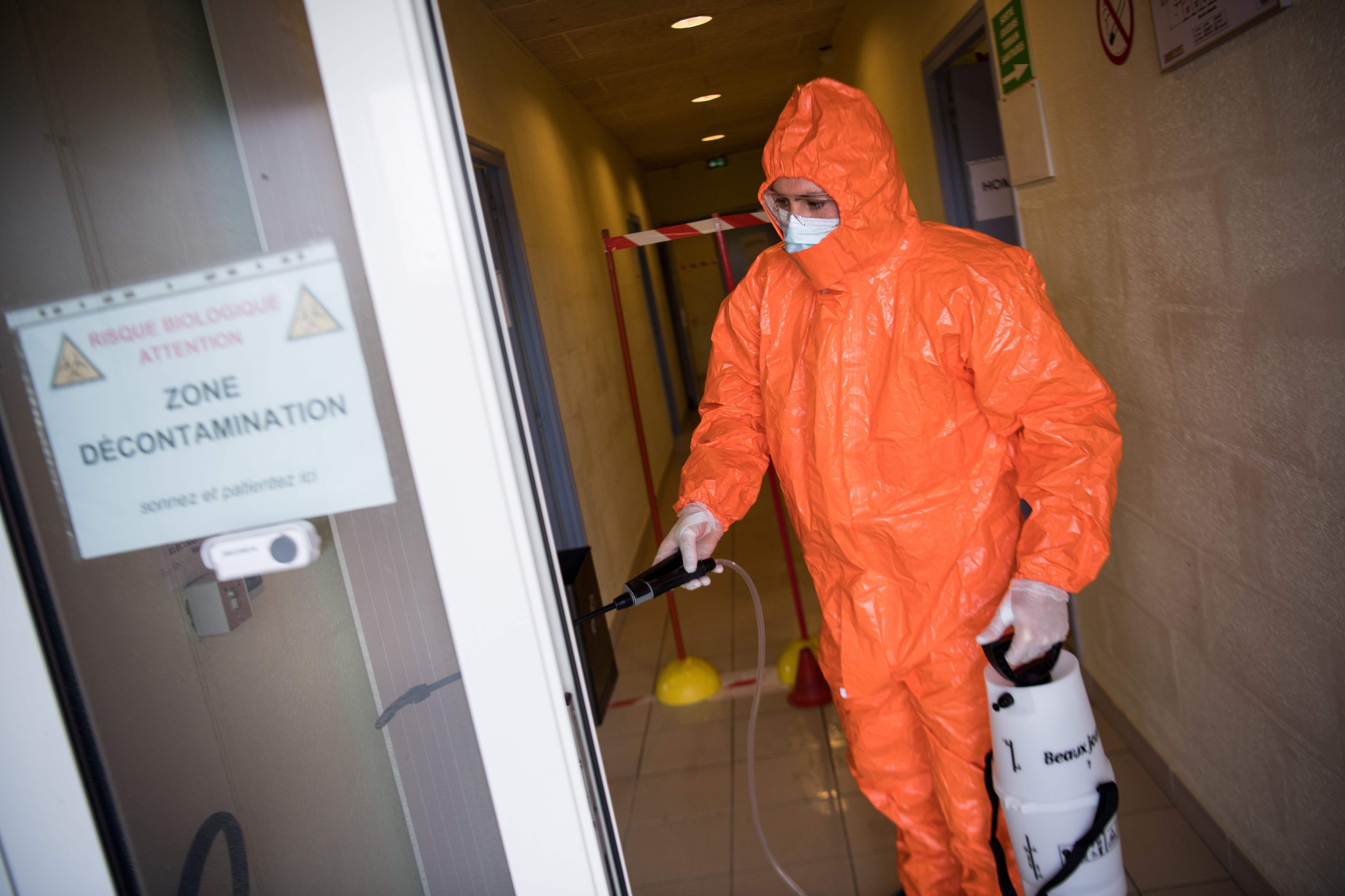 Seorang petugas menyemprotkan cairan disinfektan di sebuah pusat kebugaran yang dijadikan pusat dekontaminasi di Trignac, Prancis.