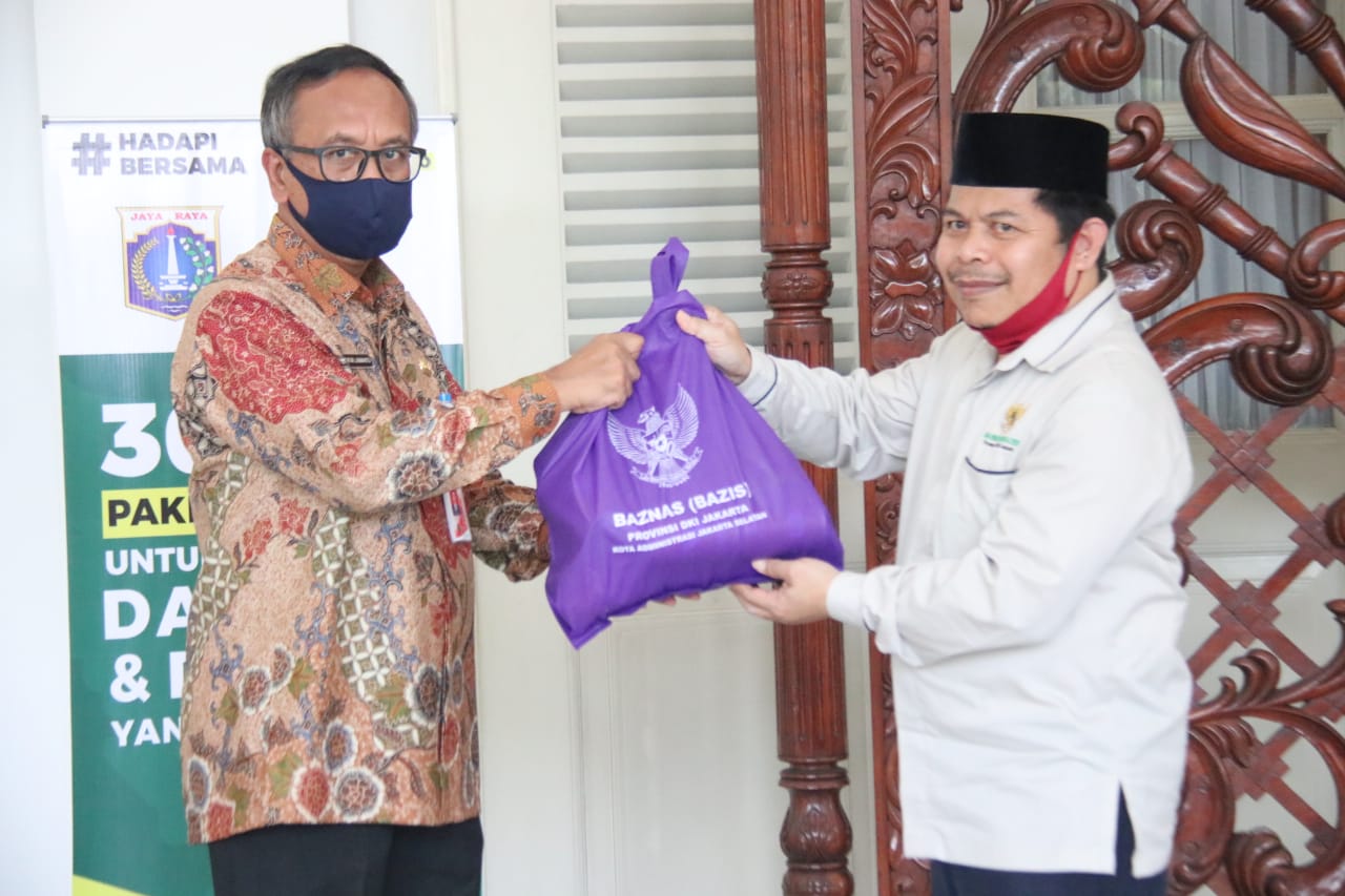  Ketua Baznas DKI Jakarta, Ahmad Luthfi Fathullah (kanan) secara simbolis serahkan bantuan ke Asisten Kesra Catur Laswanto