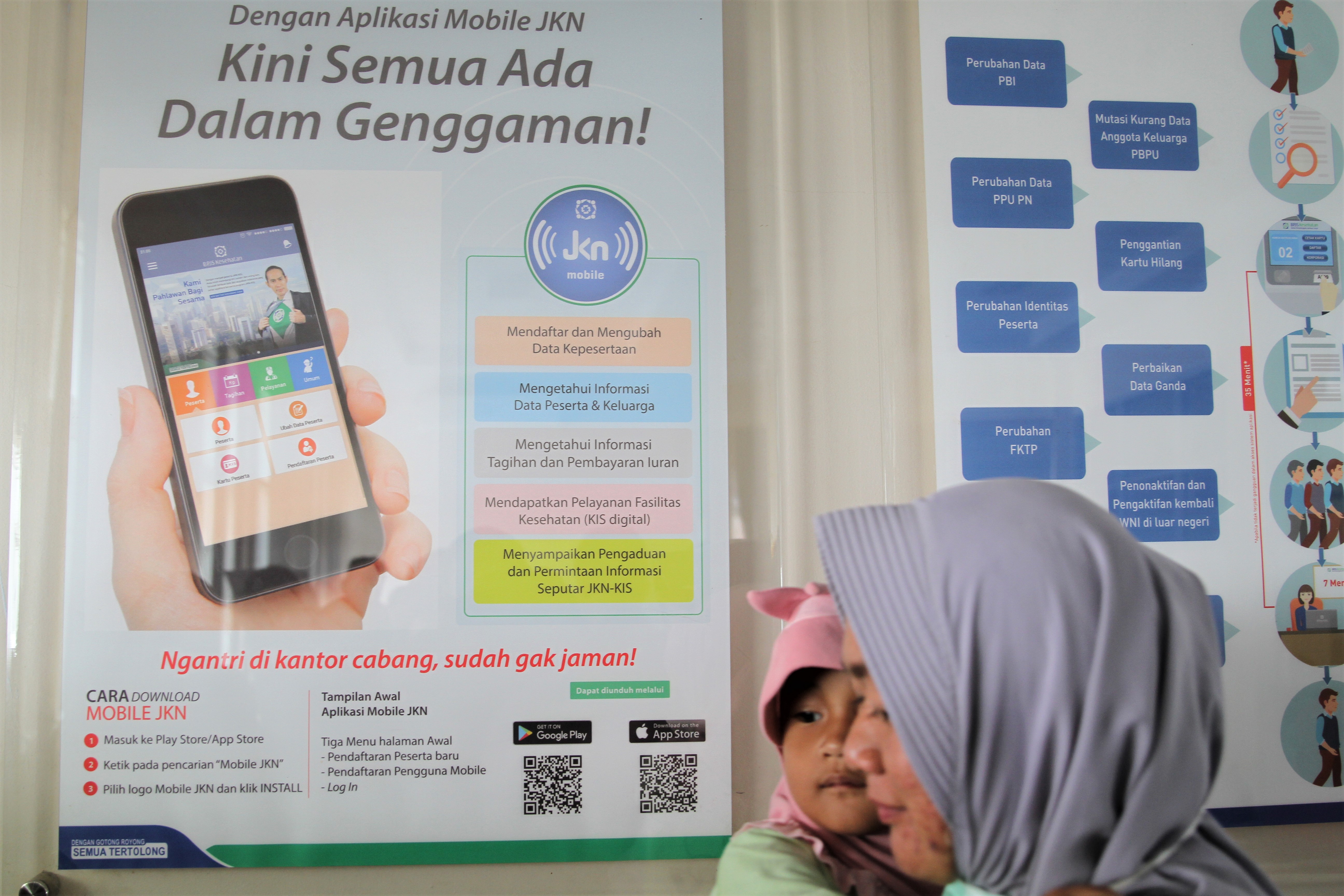 arga melintas di dekat papan informasi tentang Aplikasi Mobile Jaminan Kesehatan Nasional (JKN) di Kantor BPJS Kesehatan Kendari, Kendari.