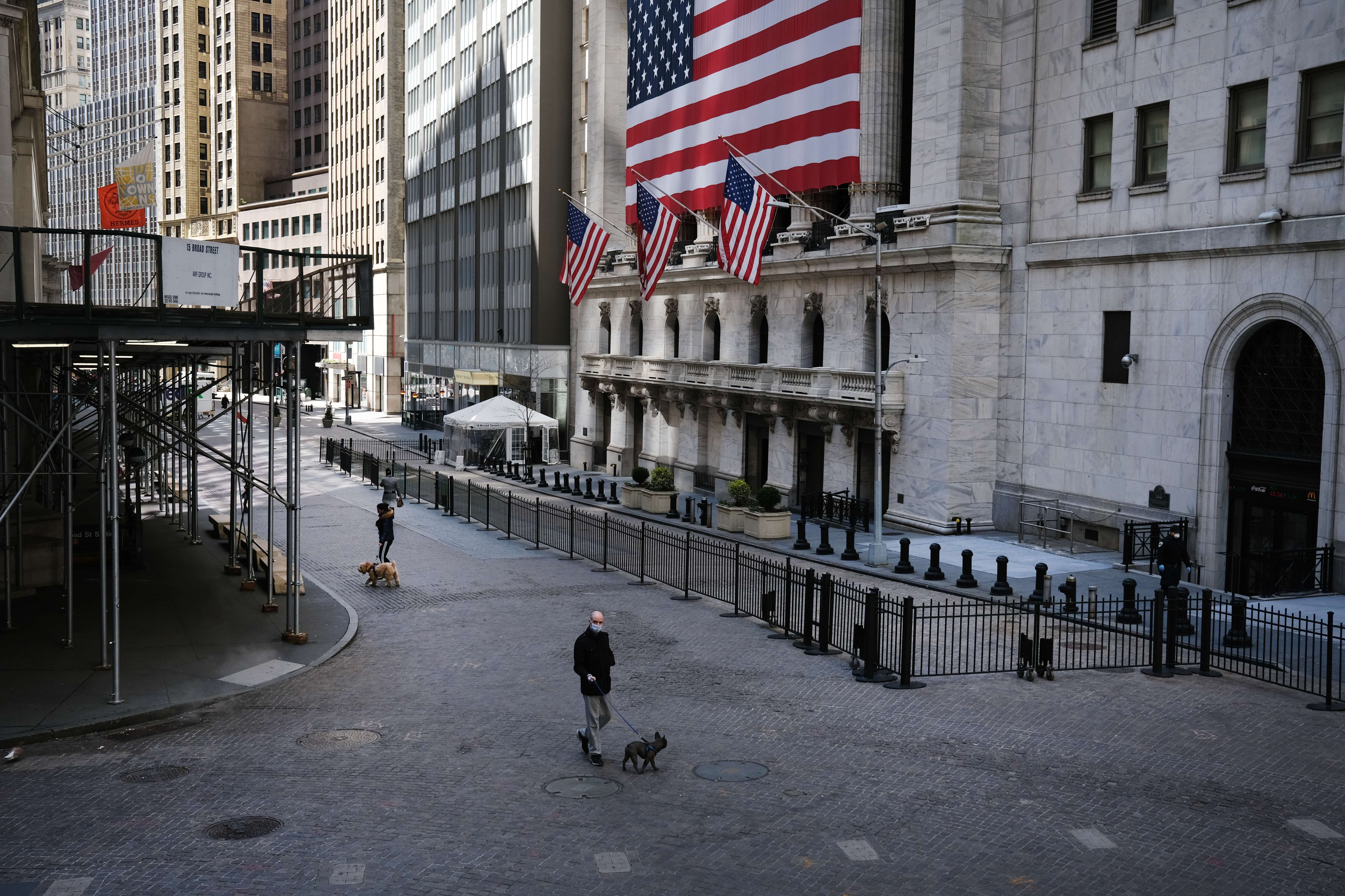 Sejumlah orang melintas di gedung bursas saham Wall Street, New York. Saham-saham di Wall Street berjatuhan, Kamis (16/4/2020) WIB.
