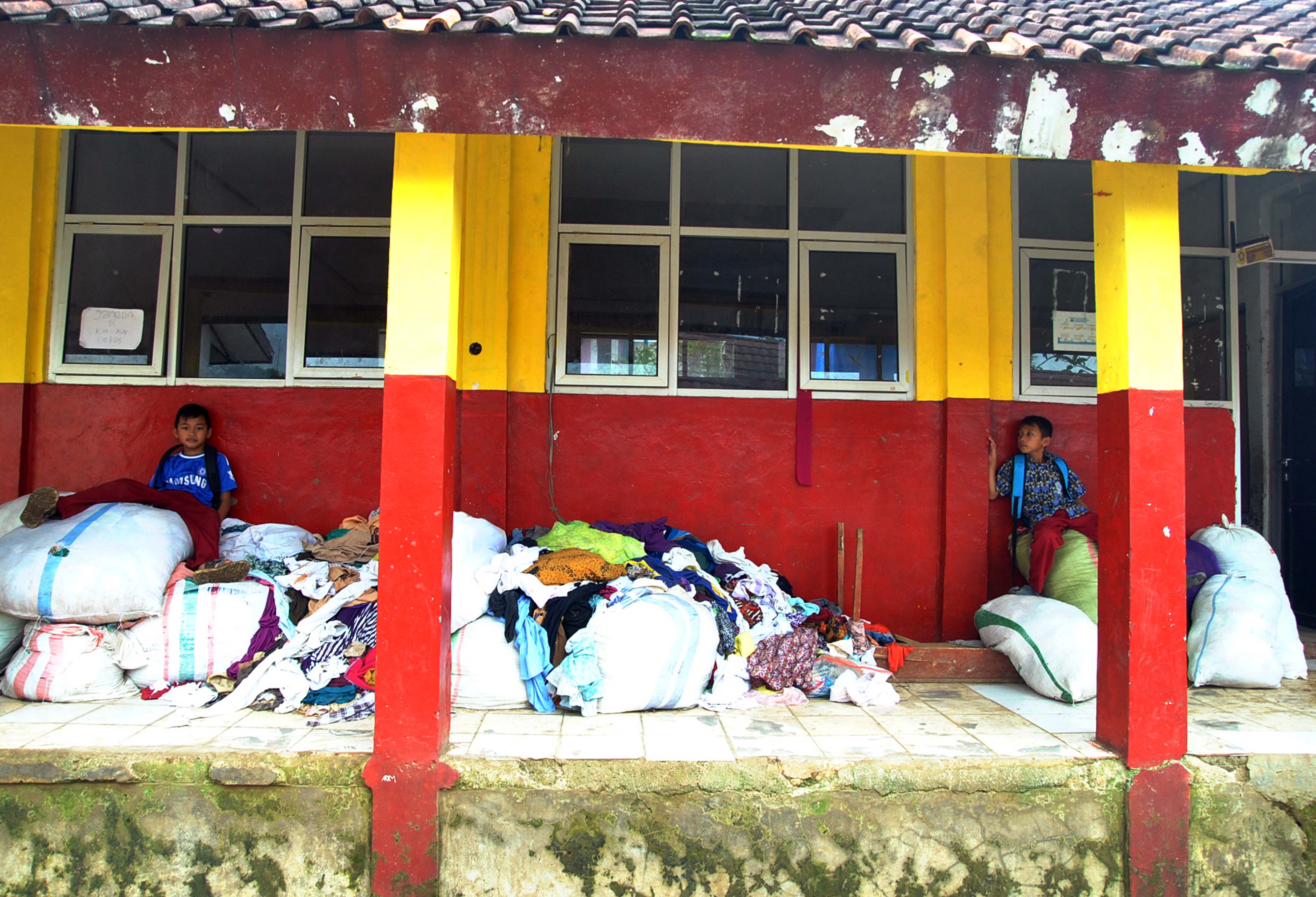  Siswa SD duduk diatas tumpukan bantuan pakaian di SDN Sukajaya 03, Desa Harkat Jaya, Kecamatan Sukajaya, Kabupaten Bogor.