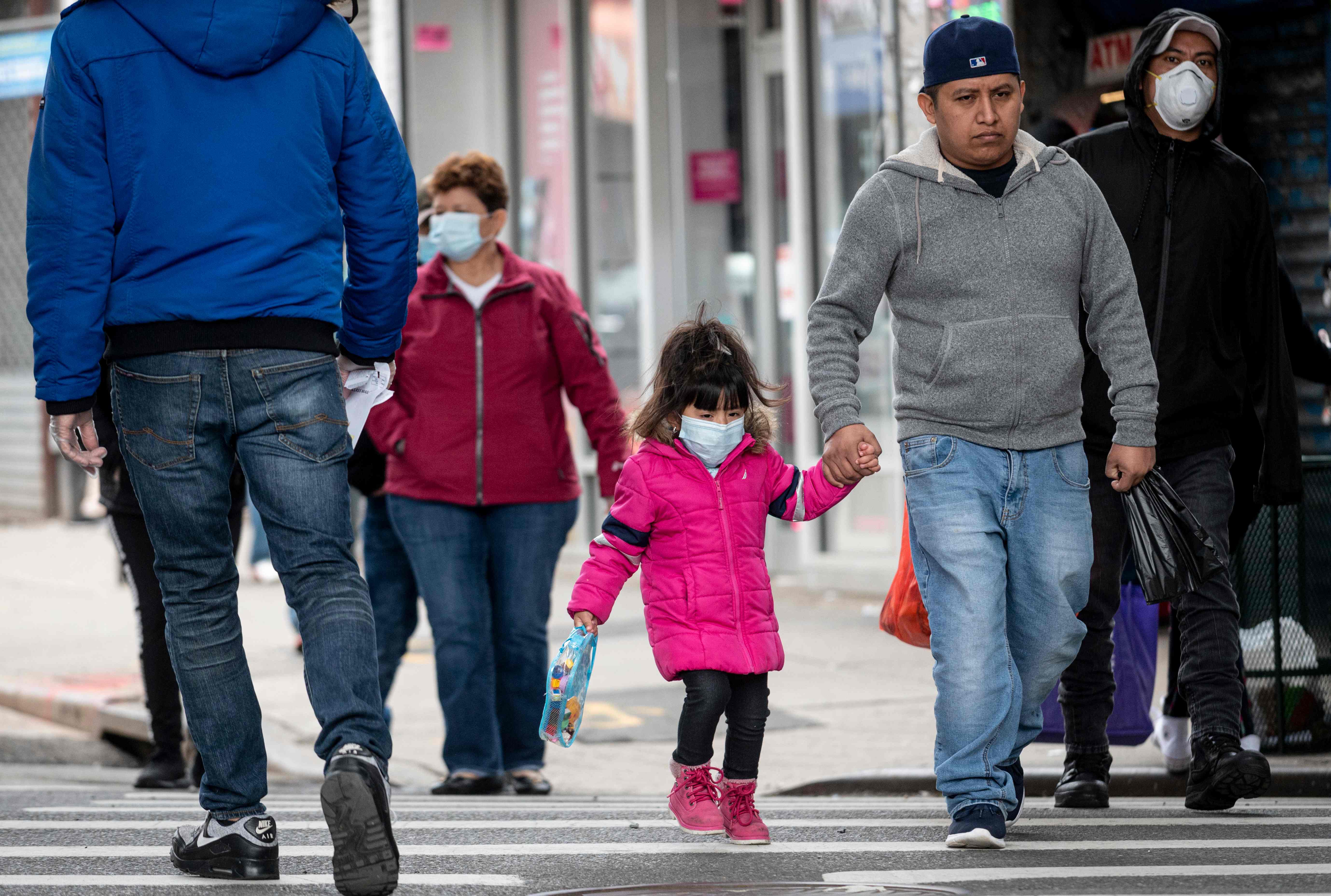 Sejumlah warga mengenakan masker berjalan di Queens, New York.