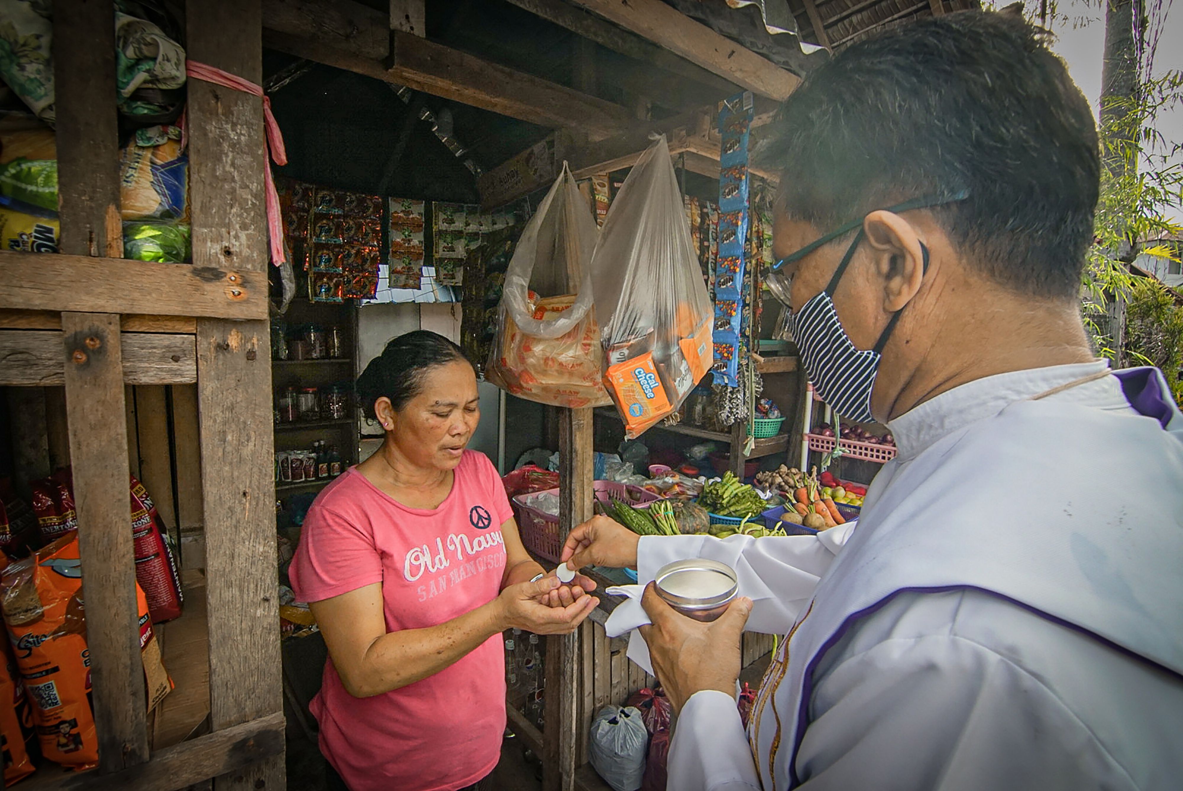 Pastor Katolik Roma, Mgr. Pepe Quitorio (kanan) memberikan komuni kepada seorang penduduk di kota Borongan, provinsi Samar Timur, Filipina.