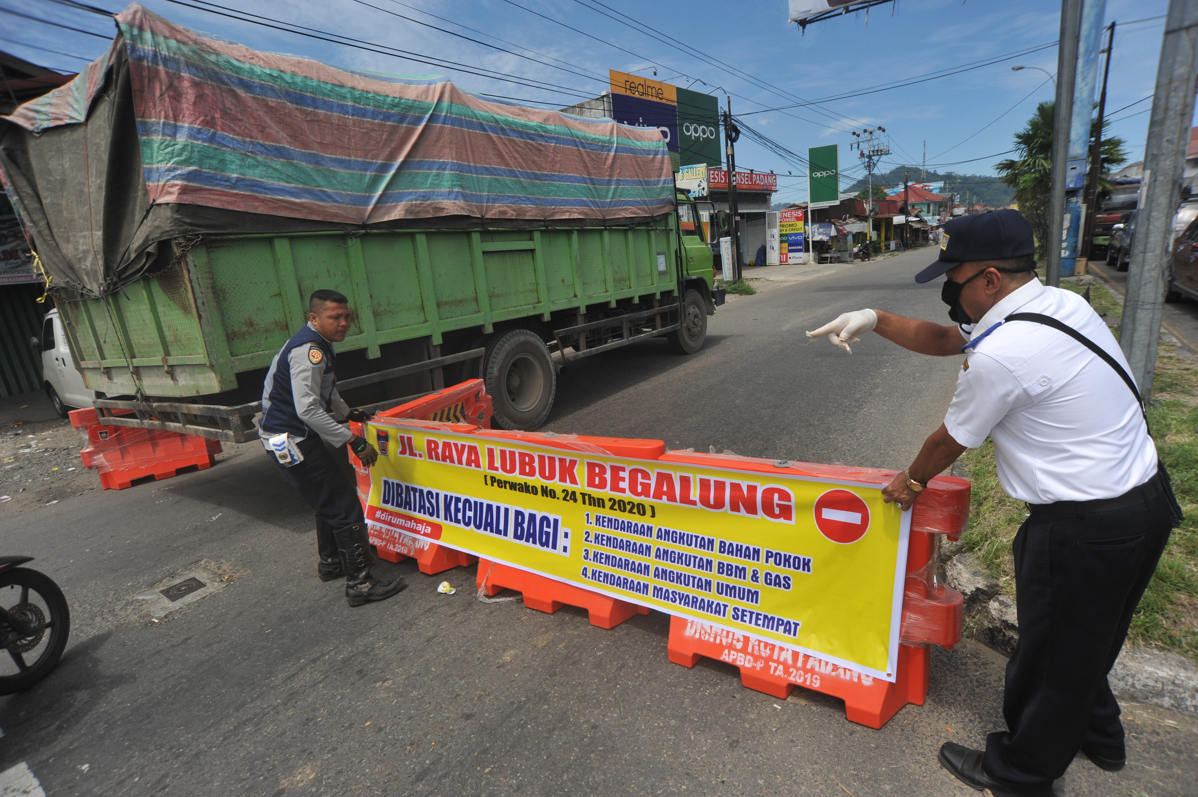 Petugas memasang spanduk berisi larangan kendaraan untuk tidak masuk kota, di Simpang Lubeg, Padang, Sumbar, Jumat (3/4/2020)