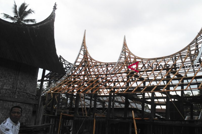 Seorang warga duduk di depan rumah adat Minangkabau, Rumah Gadang, yang direstorasi di Kawasan Saribu Rumah Gadang Nagari Koto Baru.