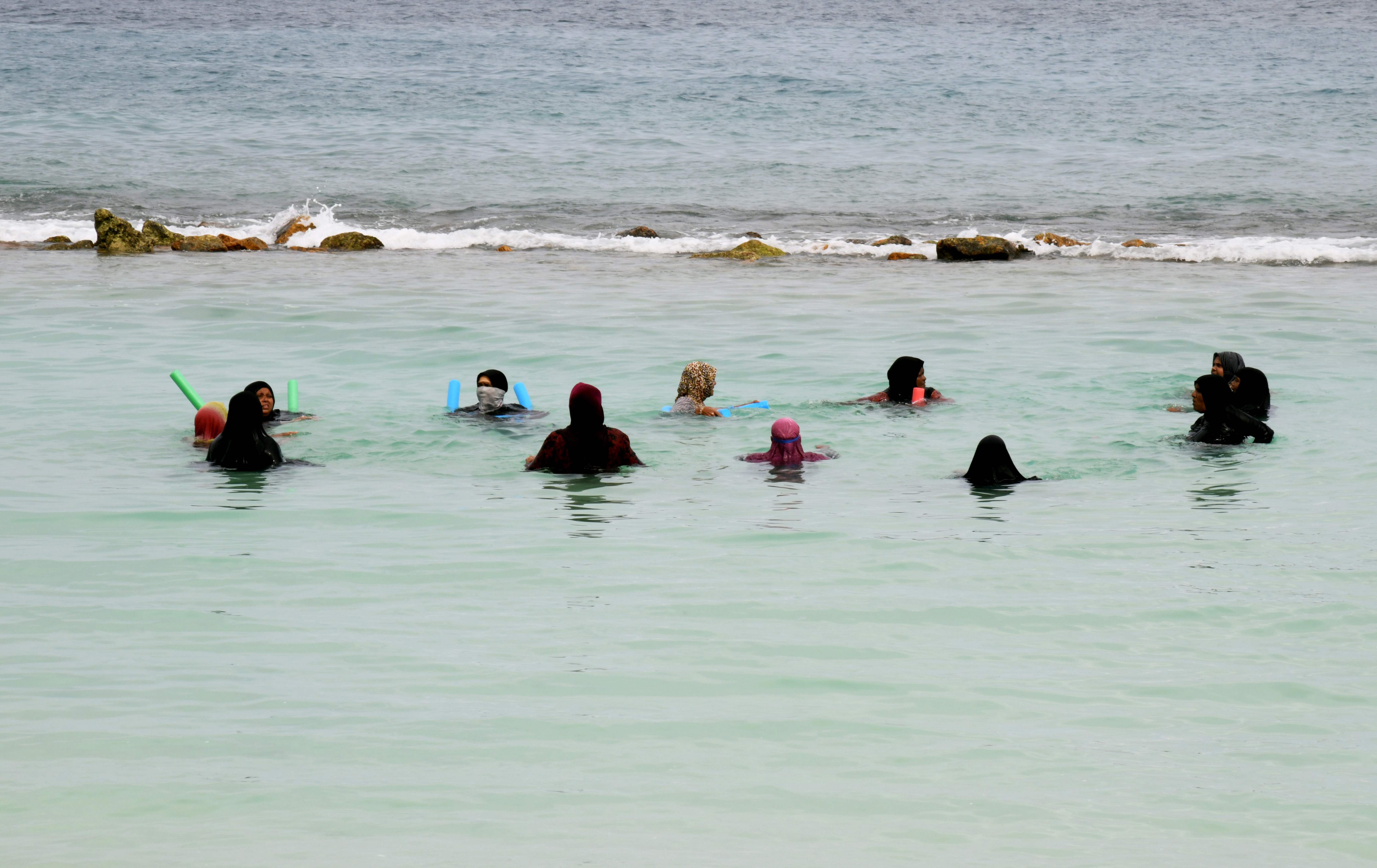 Sekelompok turis perempuan berenang di pantai buatan di Maladewa.
