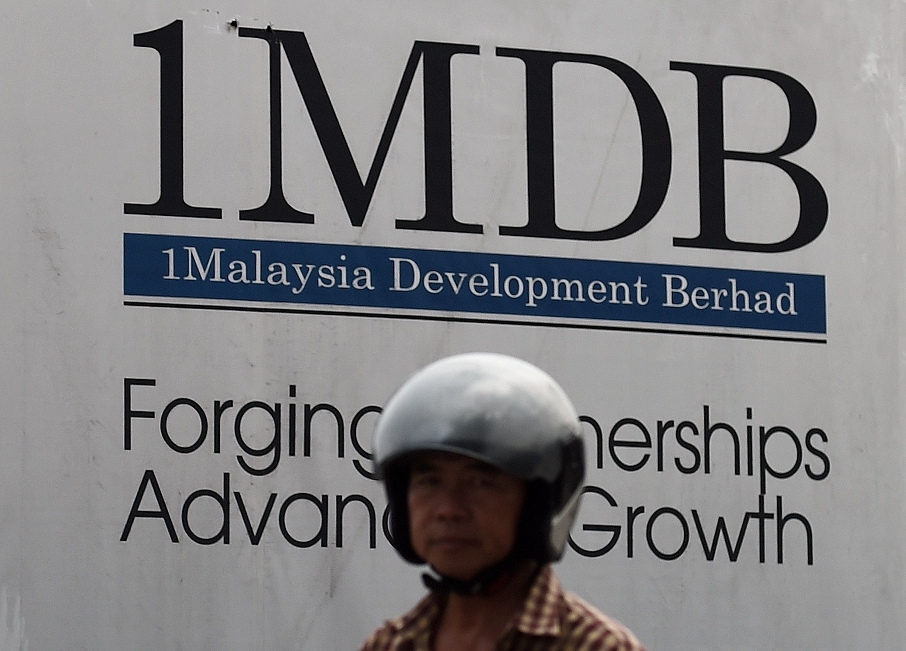 Seorang warga melintas di depan proyek pembangunan 1MDB di Kuala Lumpur, Malaysia.
