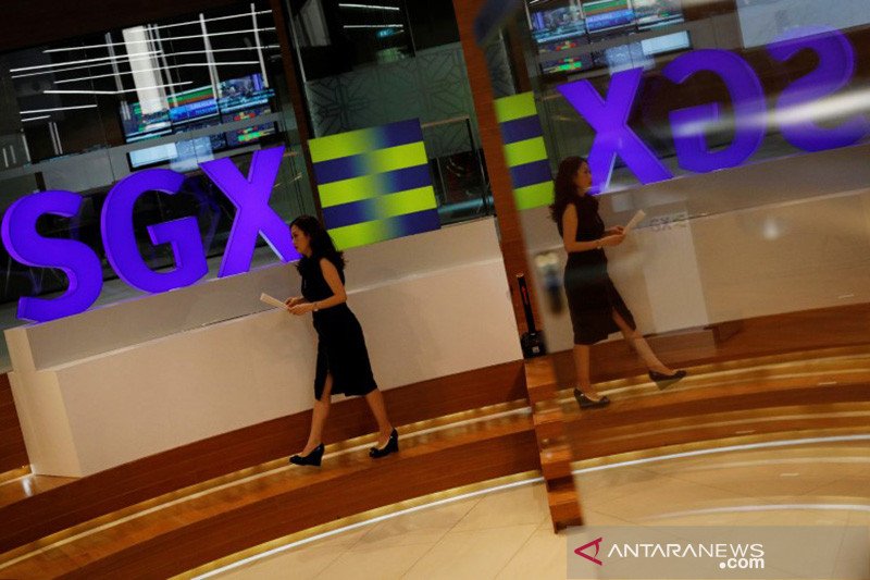 Seorang pekerja melintas di logo SGX (Singapore Stock Exchange).