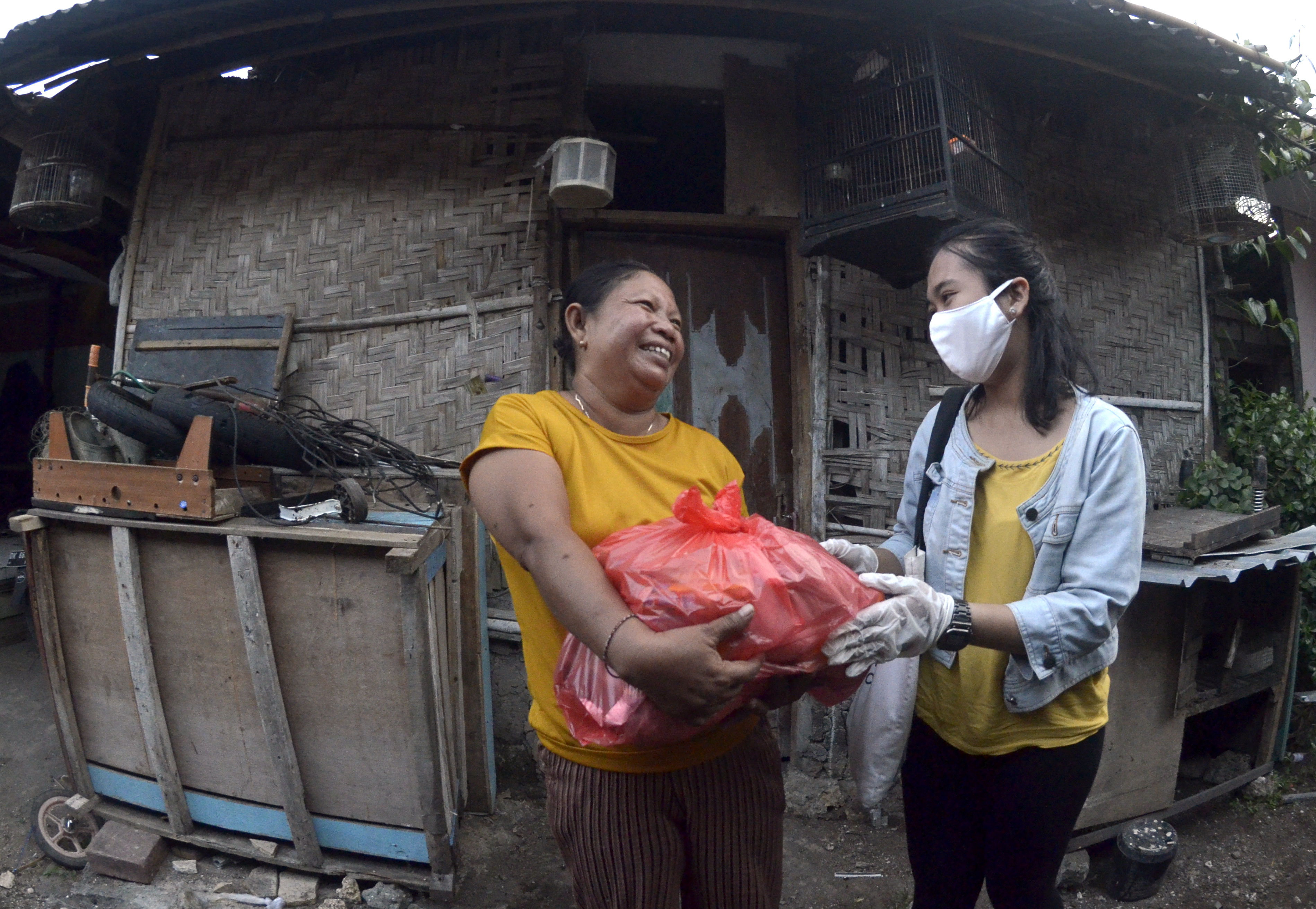 Relawan memberikan paket sembako kepada warga yang membutuhkan di kawasan Jimbaran, Badung, Bali.