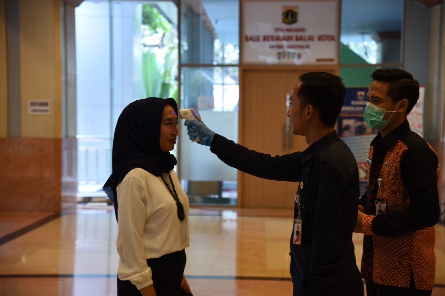 Petugas melakukan pengecekan suhu tubuh bagi para aparatur sipil negara (ASN) maupun warga yang berkunjung ke Gedung Balai Kota, Jakarta.