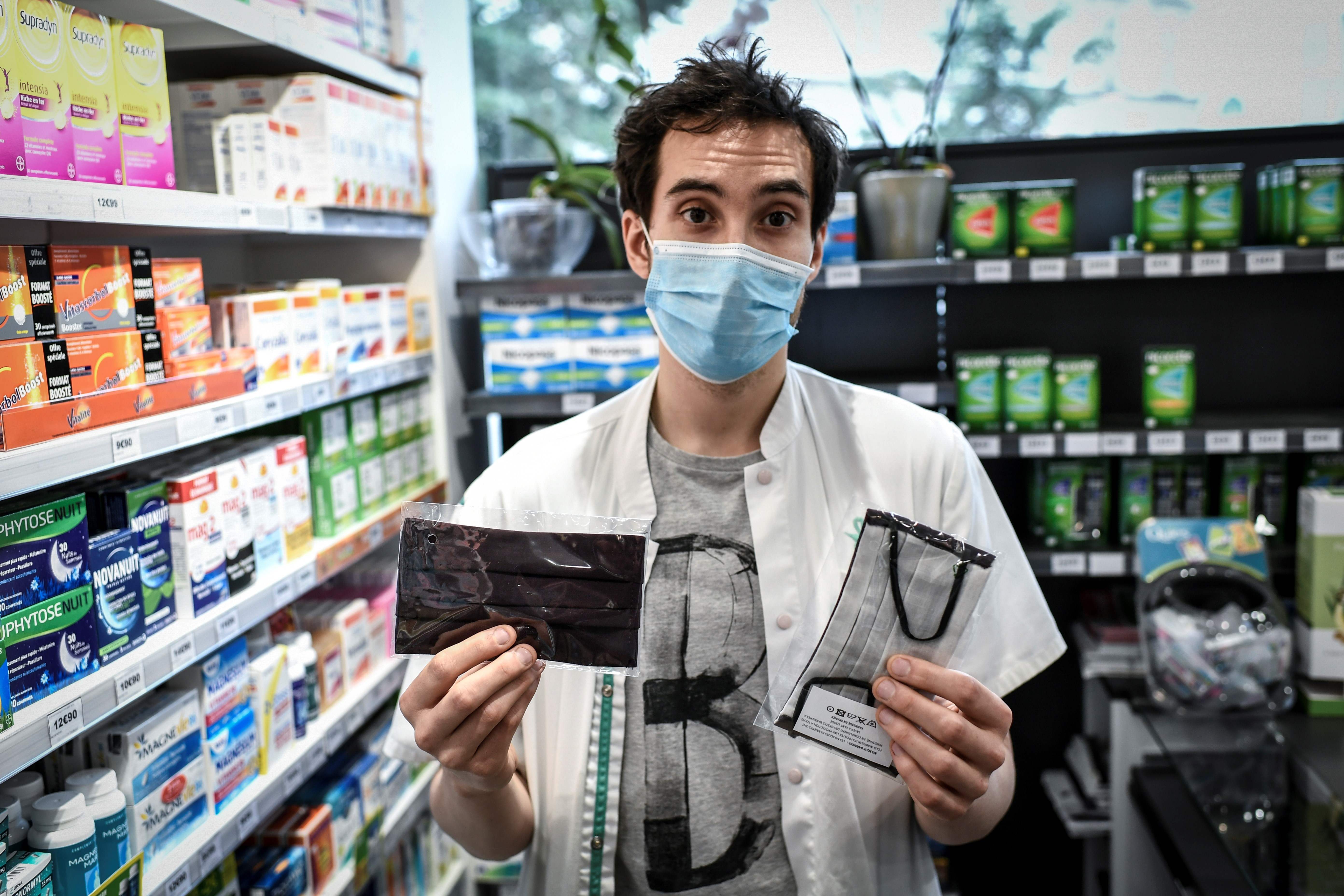Seorang apoteker menunjukkan masker kain yang dijual di apotek di Paris, Prancis.
