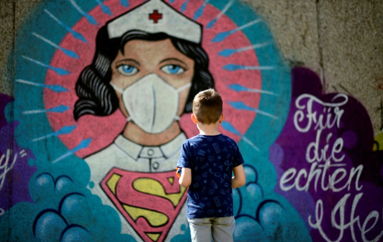 Seorang anak melihat mural karya seniman Kai 'Uzey' Wohlgemuth yang menggambarkan perawat sebagai 'Superwoman' di Hamm, Jerman.