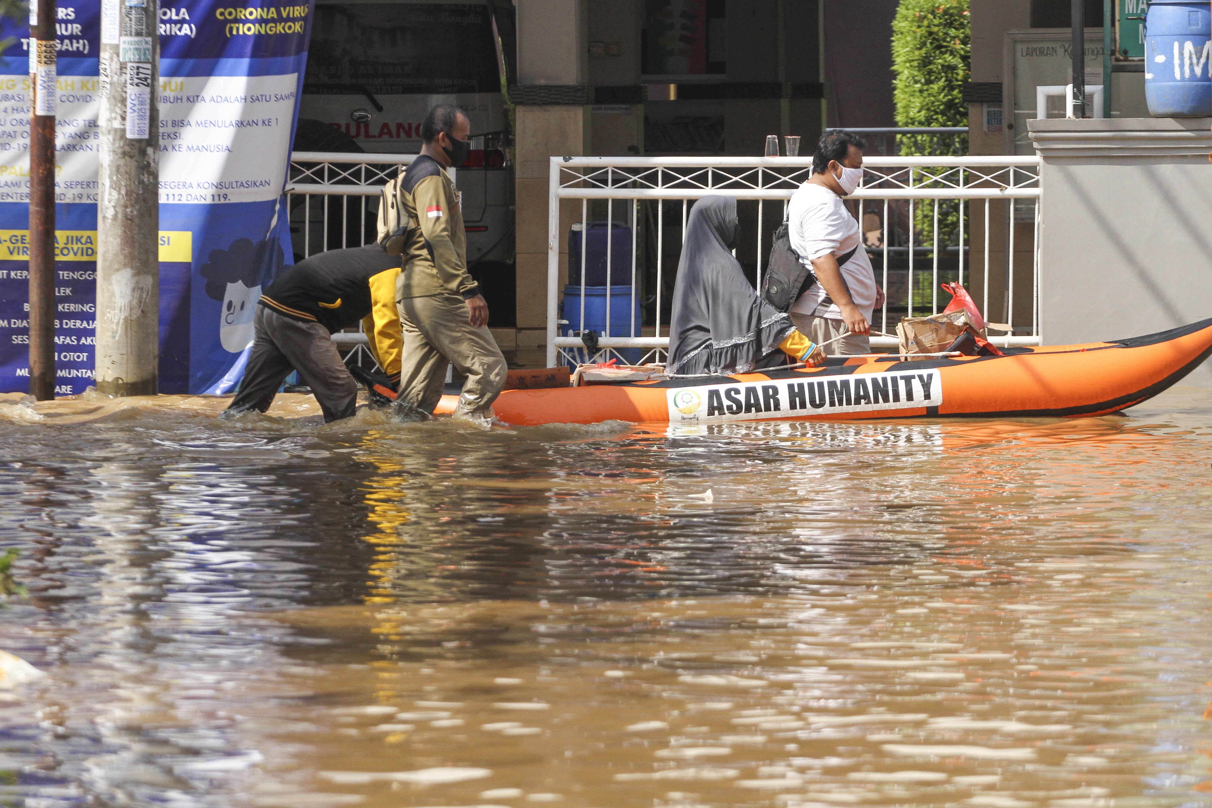 Warga melintas menggunakan perahu karet ditengah banjir di Bukit Sawangan Indah, Depok, Jawa Barat, hari ini.