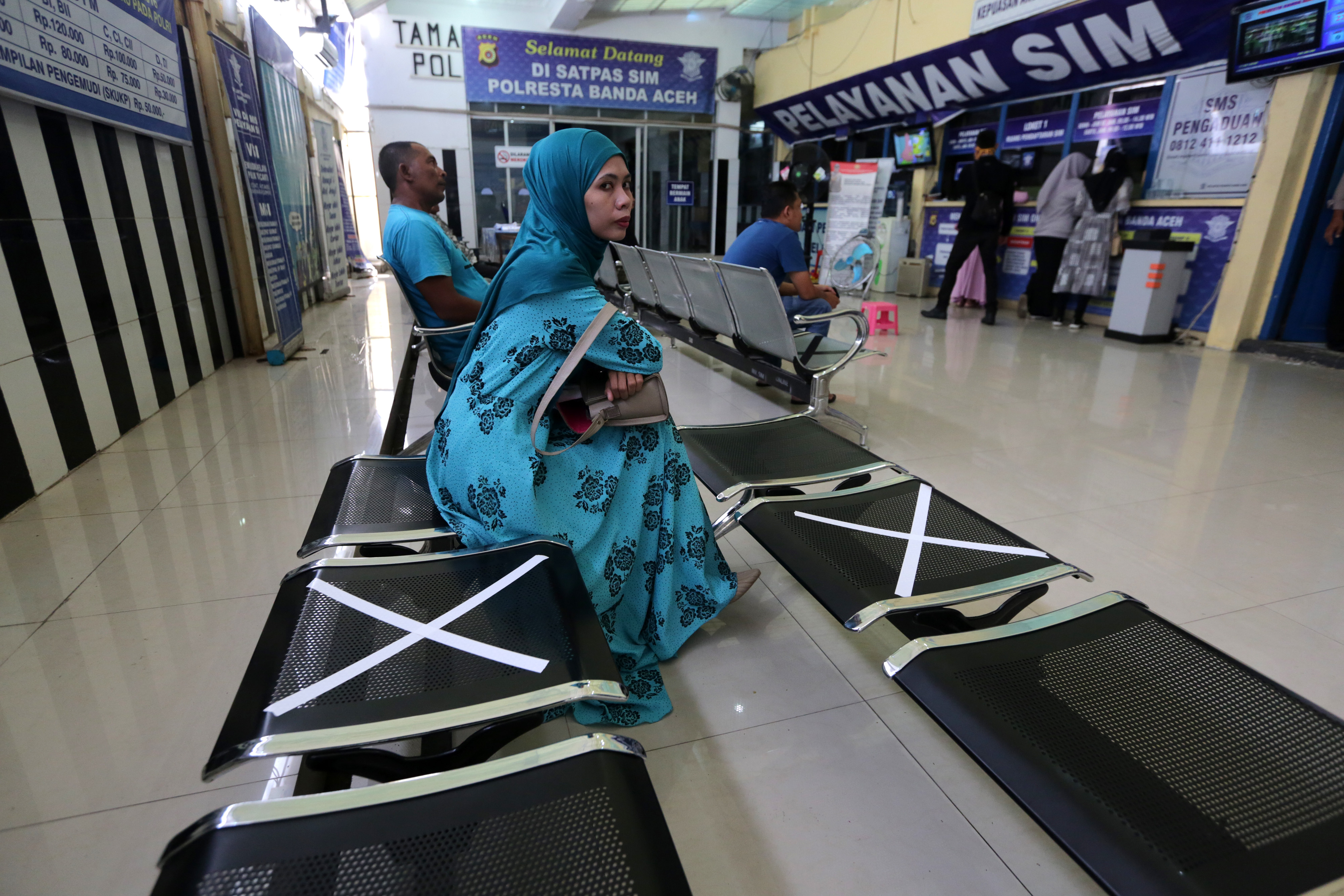 Warga antre pembuatan dan perpanjangan Surat Izin Mengemudi (SIM) di ruang tunggu yang telah diberi tanda jarak di Mapolresta Banda Aceh.