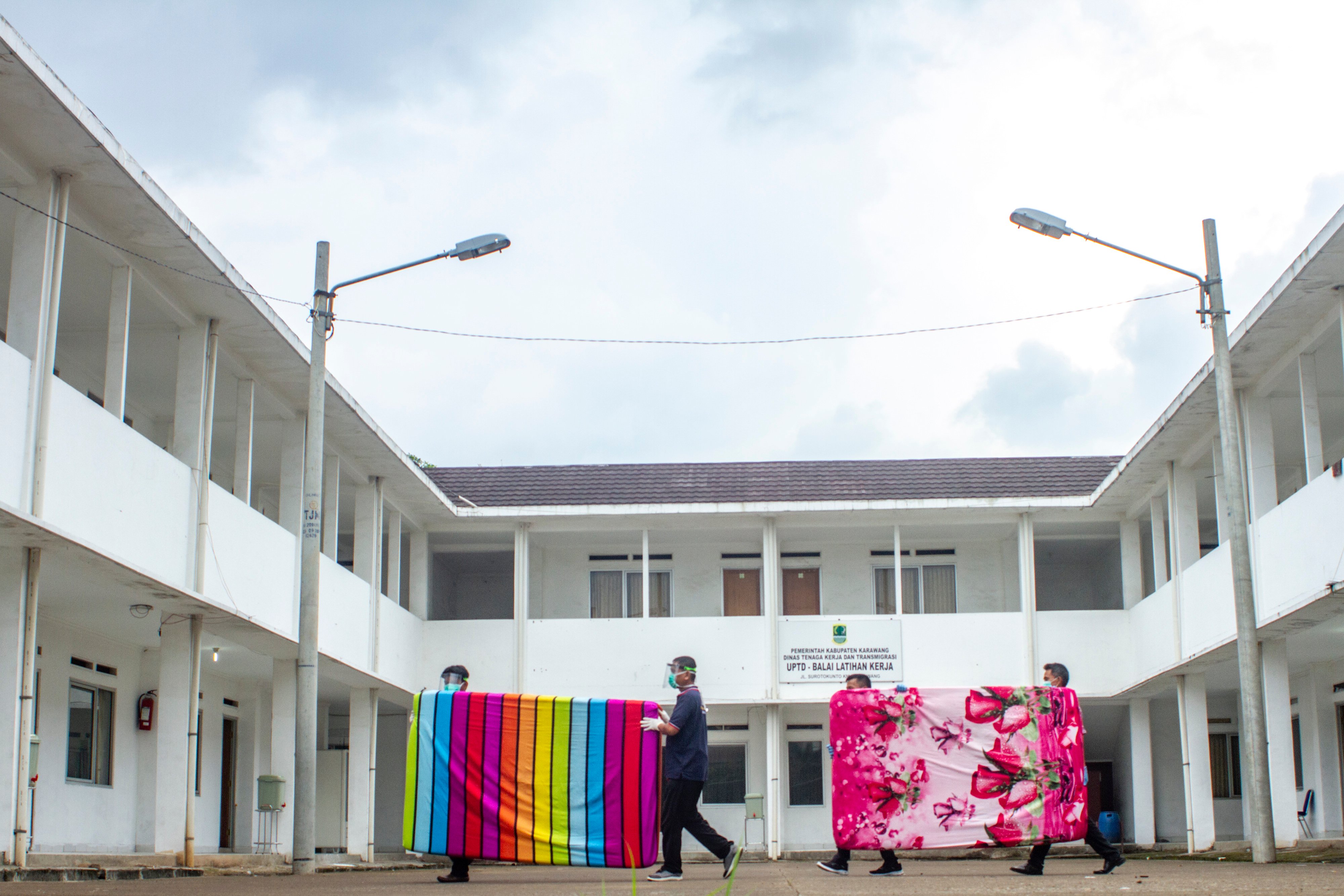 Petugas membawa kasur di halaman ruangan pemulihan pasien sembuh covid-19 di Karawang, Jawa Barat, Kamis (23/4).