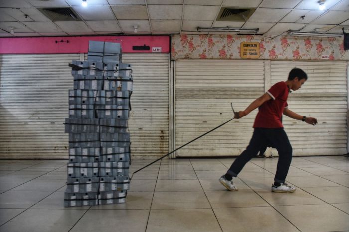 Seorang karyawan menarik tumpukan sepatu di tengah penutupan Blok M Mall akibat pandemi covid-19
