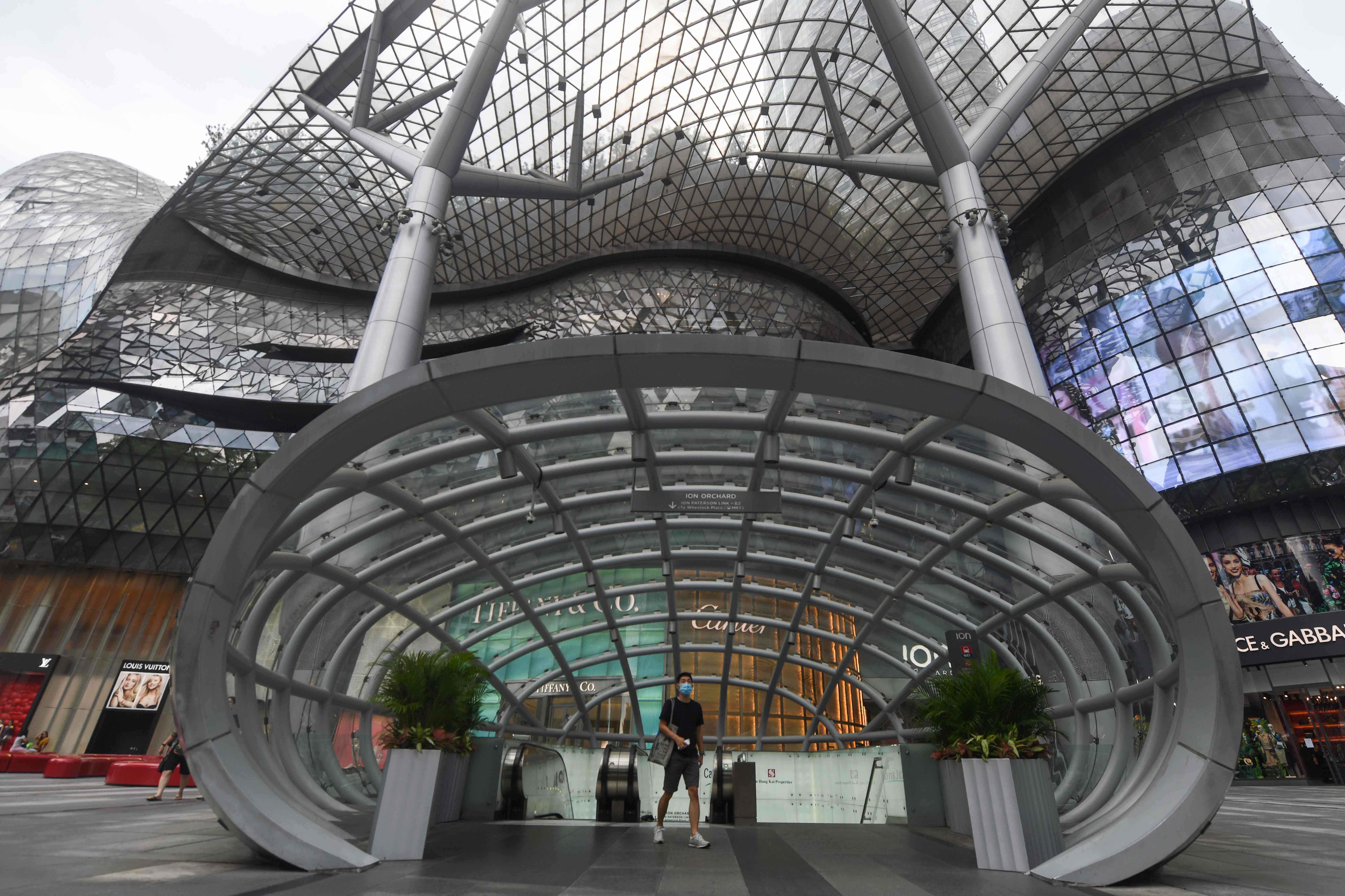 Seorang warga mengenakan masker meninggalkan sebuah pusat perbelanjaan di Orchard Road, Singapura.