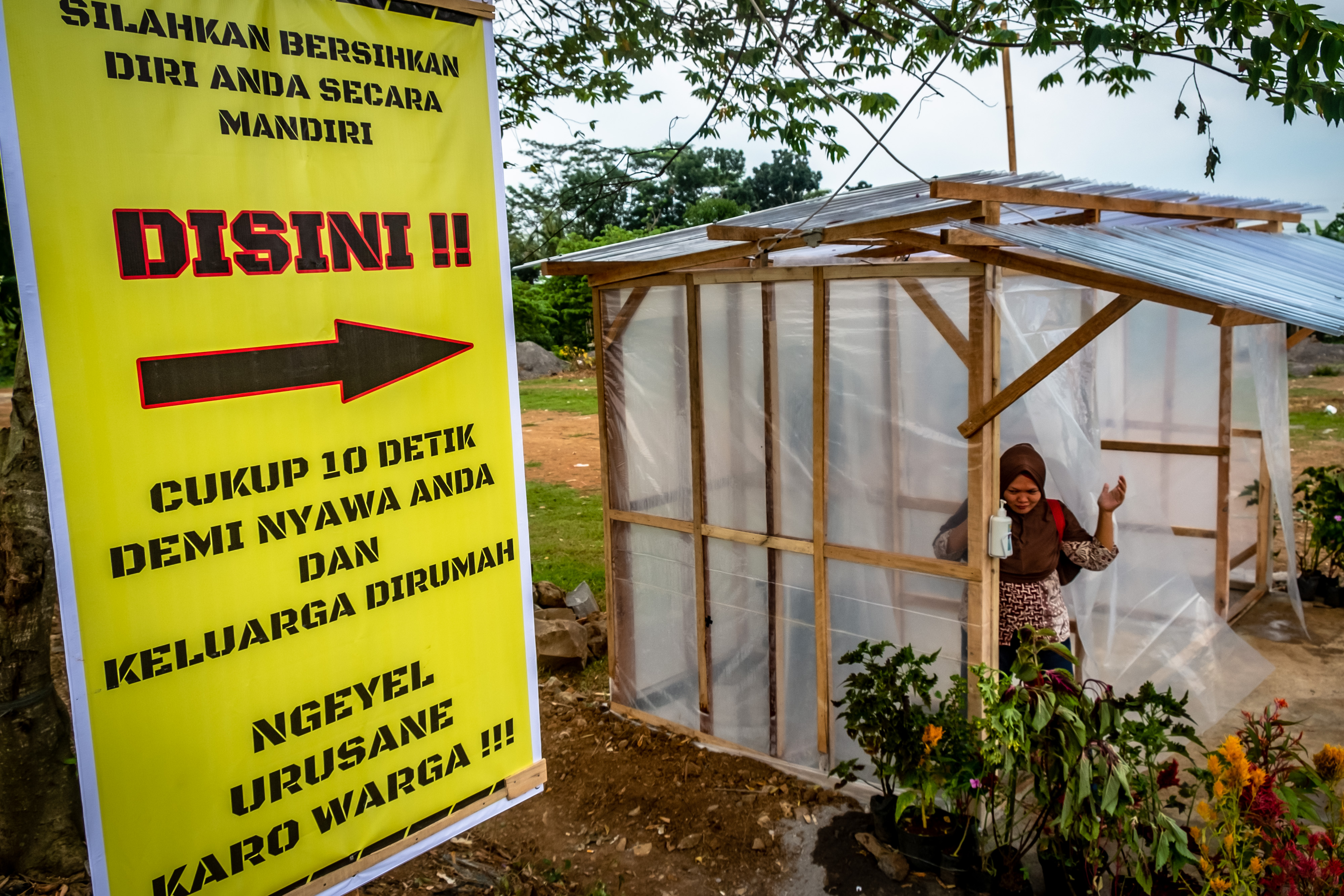 Warga keluar dari bilik disinfektan di Kabupaten Semarang, Jawa Tengah, Jumat (27/3/2020).