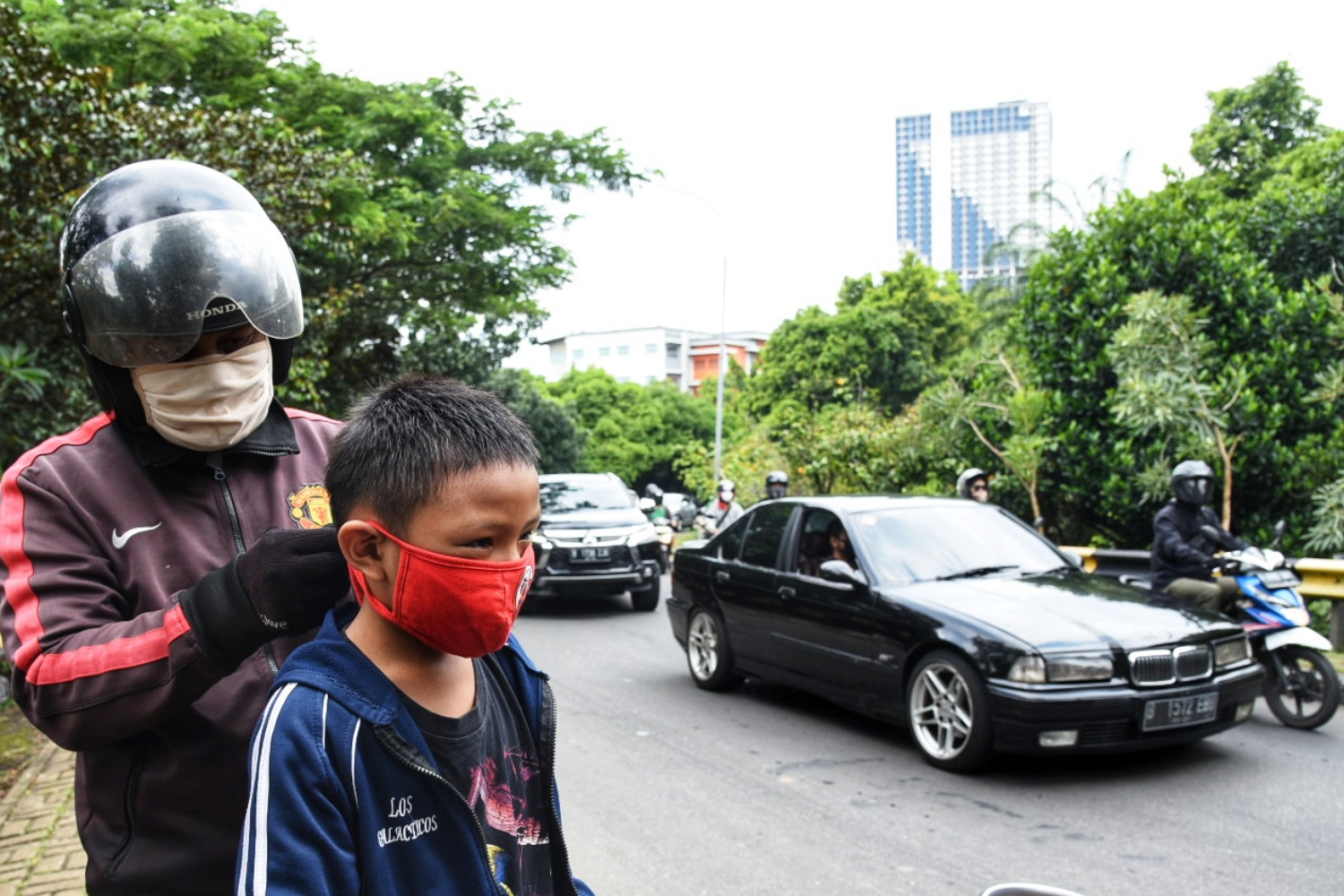 Seorang warga memakaikan masker kain pada putranya