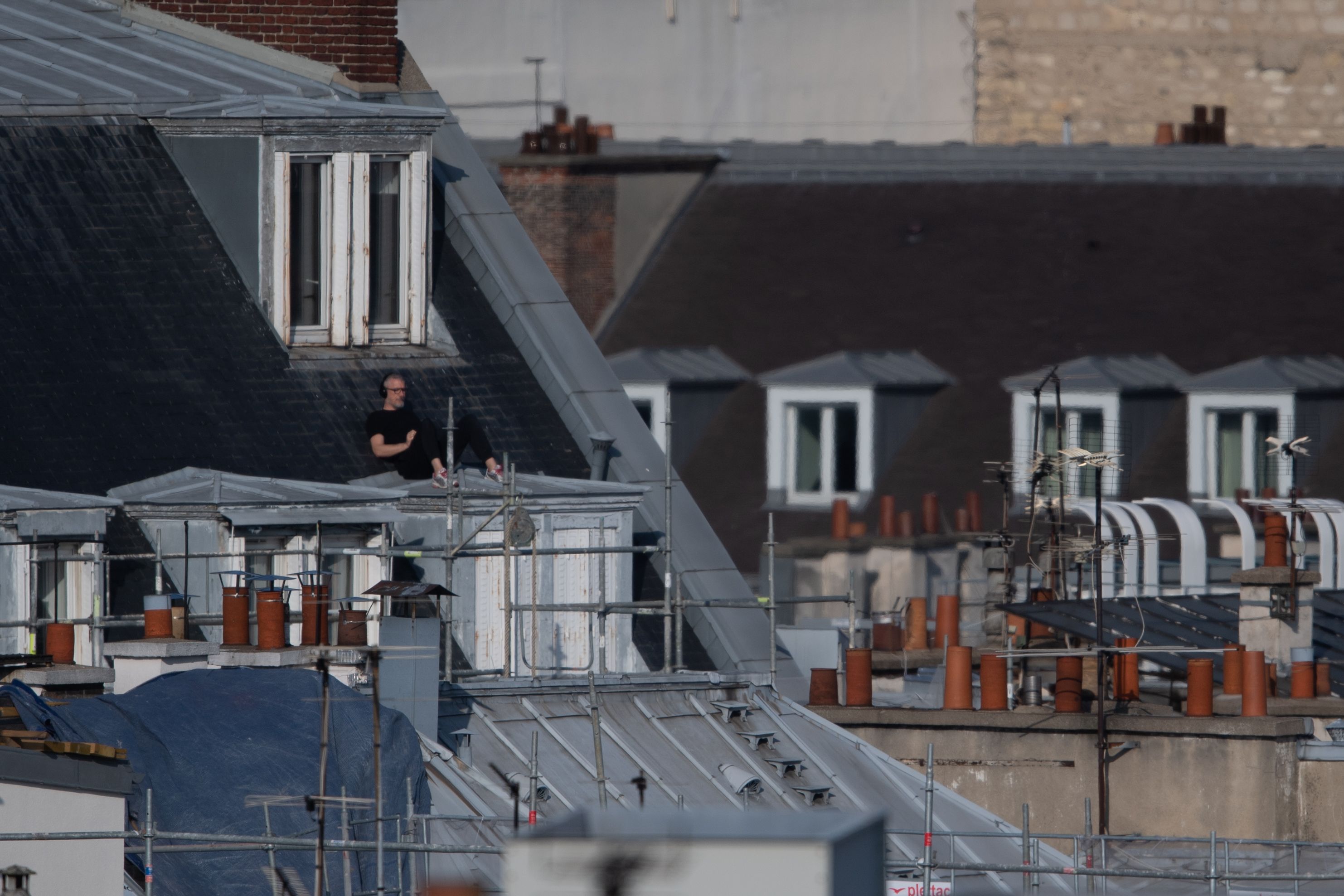 Seorang pria menikmati sinar matahari di atap rumahnya di Paris (13/4)