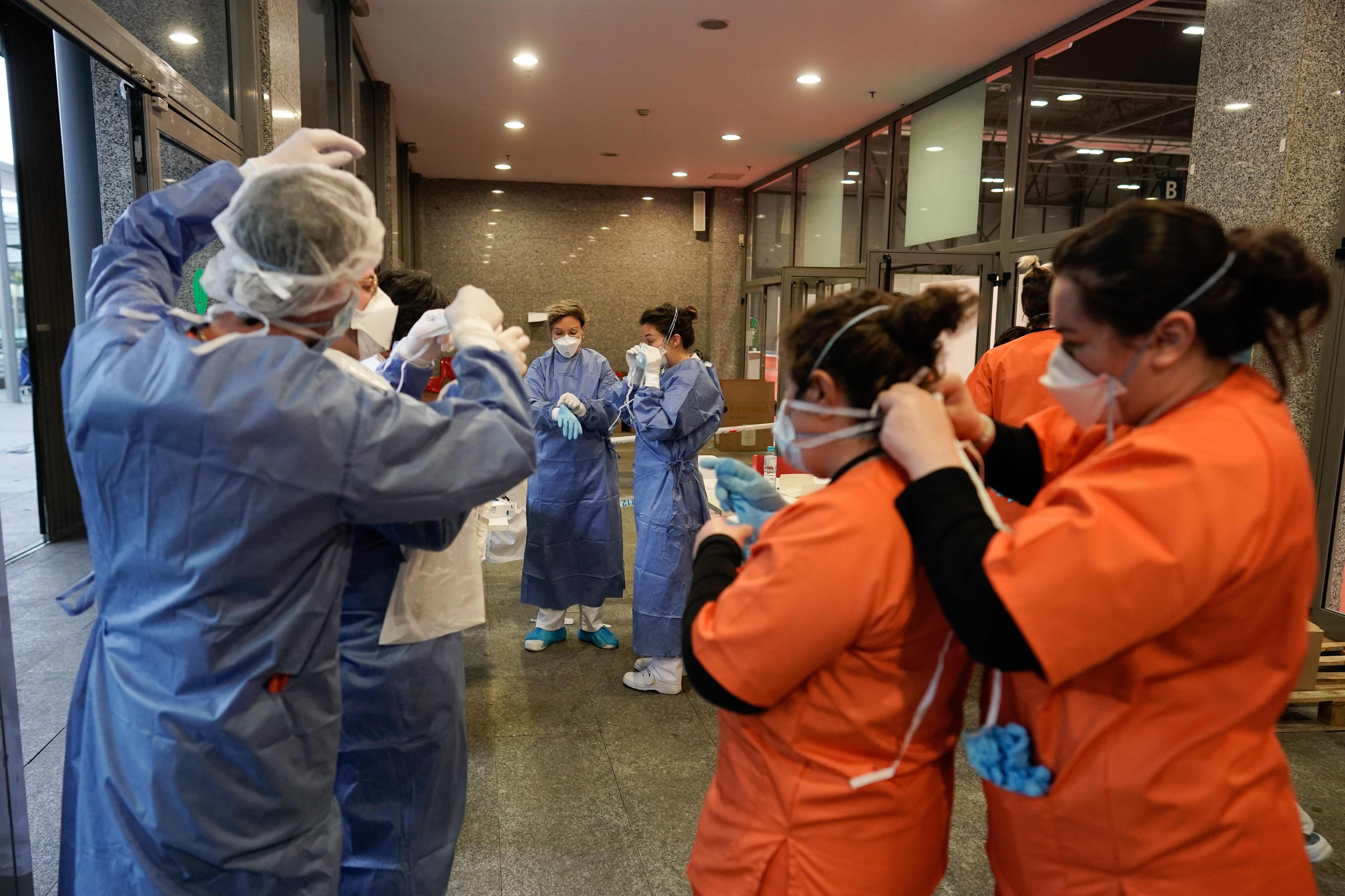 Petugas medis saling membantu mempersiapkan diri sebelum menjalankan tugas di rumah sakit darurat Covid-19 di Madrid, Spanyol.