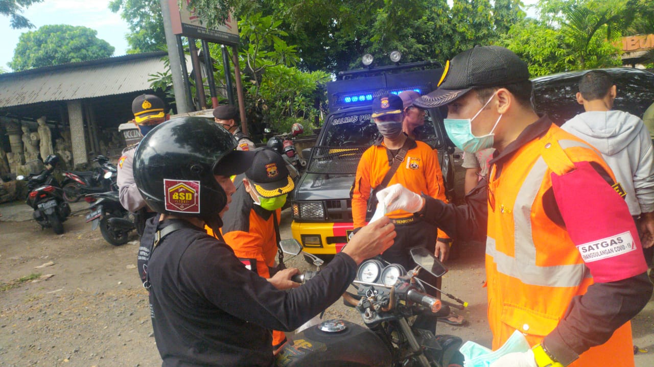 Petugas  Satgas Percepatan Penanganan Covid-19 Bali membagikan masker kepada pengendara motor di Denpasar, Selasa (14/4/2020).