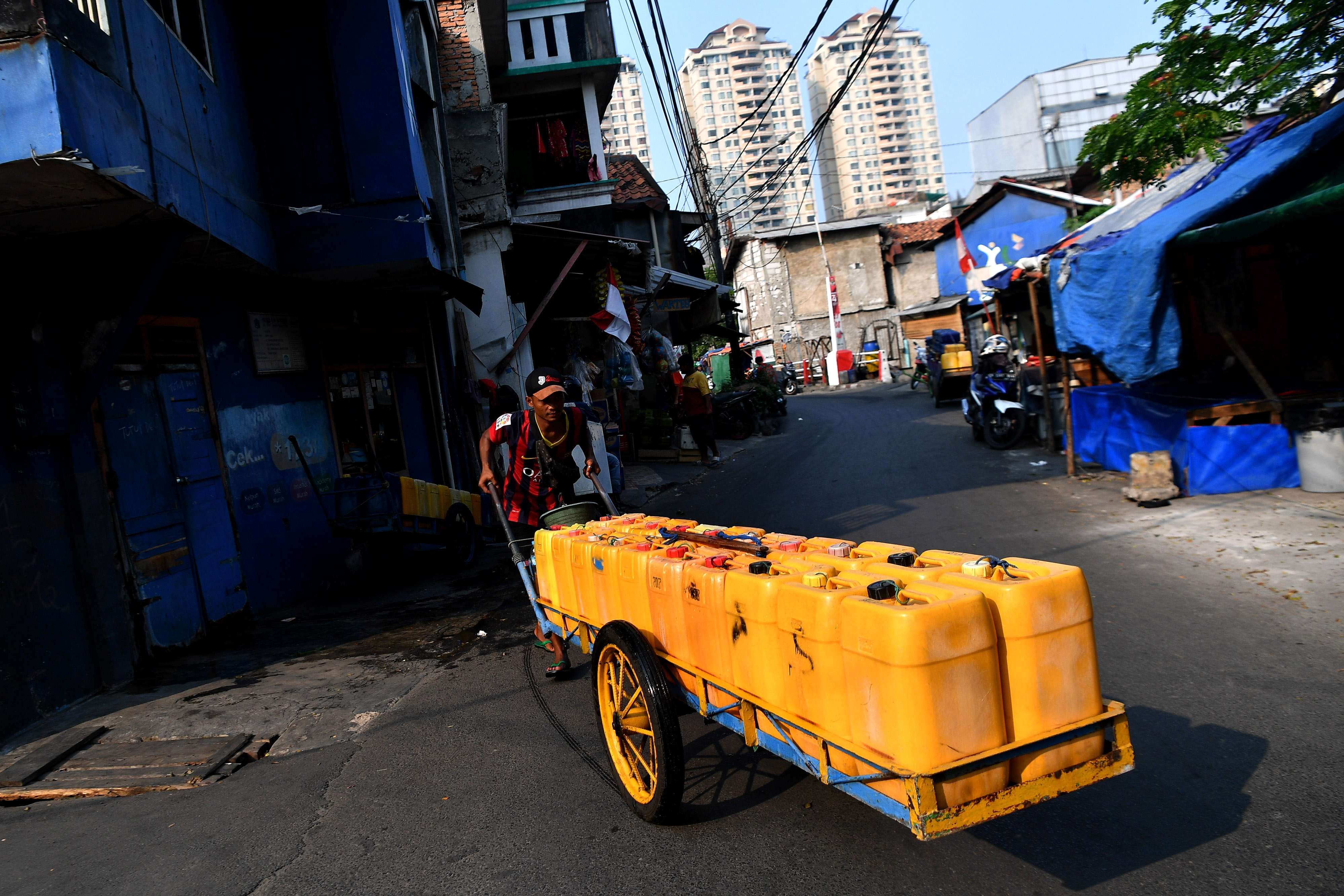 Warga mendorong jeriken berisi air bersih untuk dijual di kawasan Sawah Besar, Jakarta