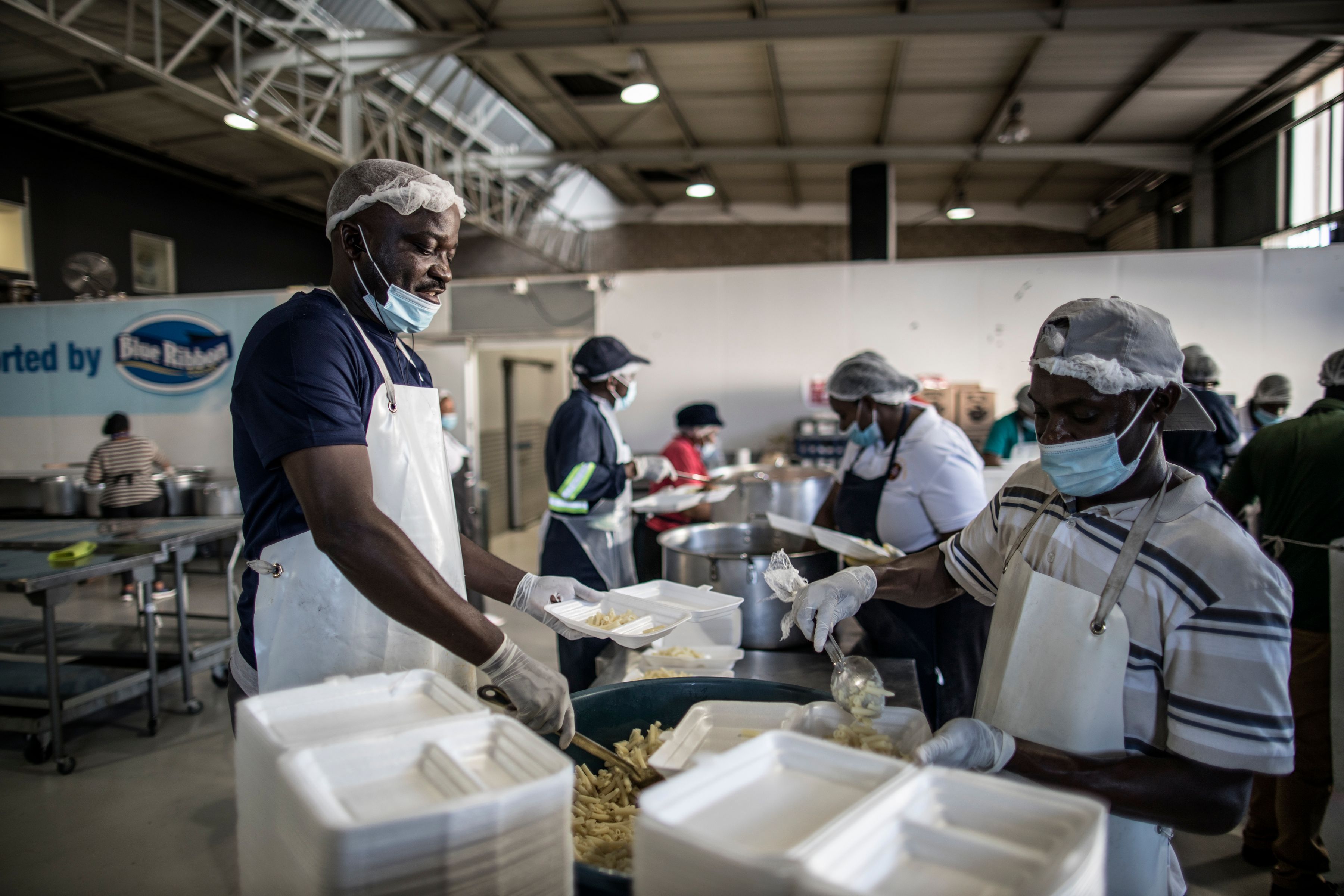 Relawan membagikan paket makanan kepada warga tuna wisma di Johannesburg, Afrika Selatan.