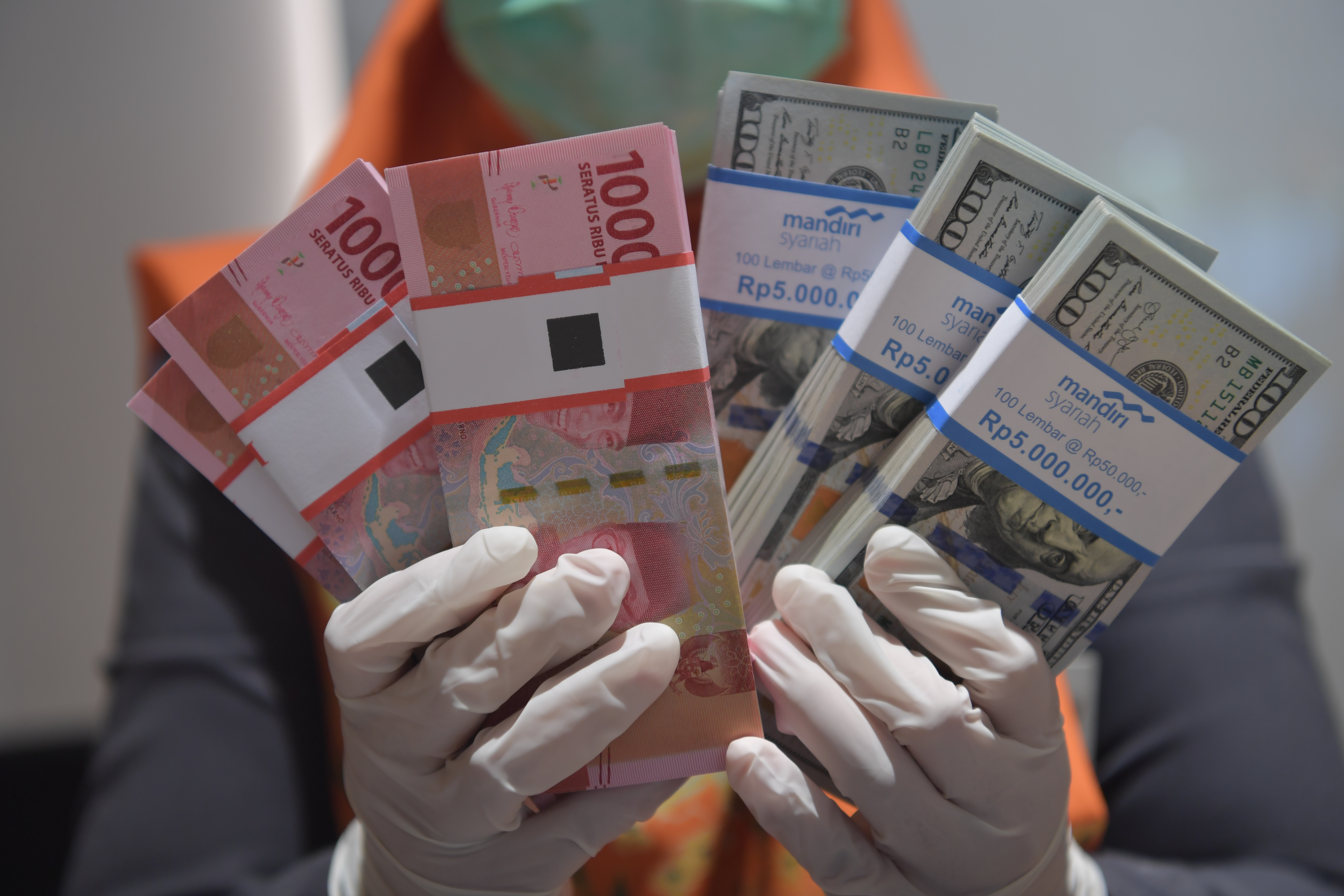 Pegawai bank menunjukan uang  rupiah dan dolar AS. 