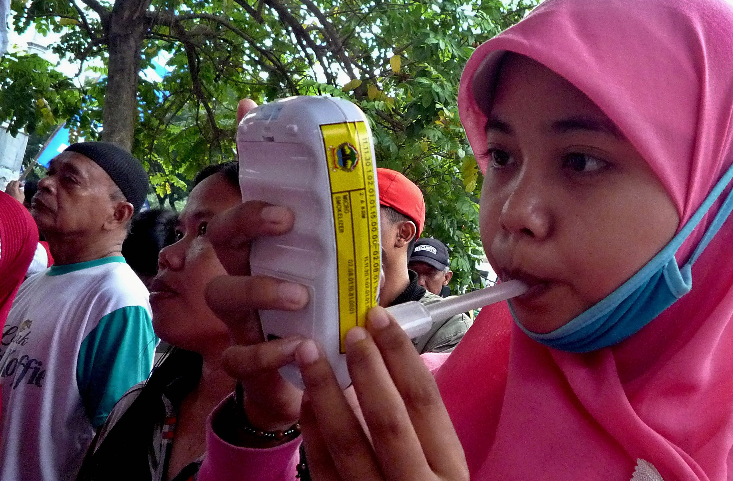 TES PARU: Seorang warga melakukan tes kesehatan paru-paru dengan alat 