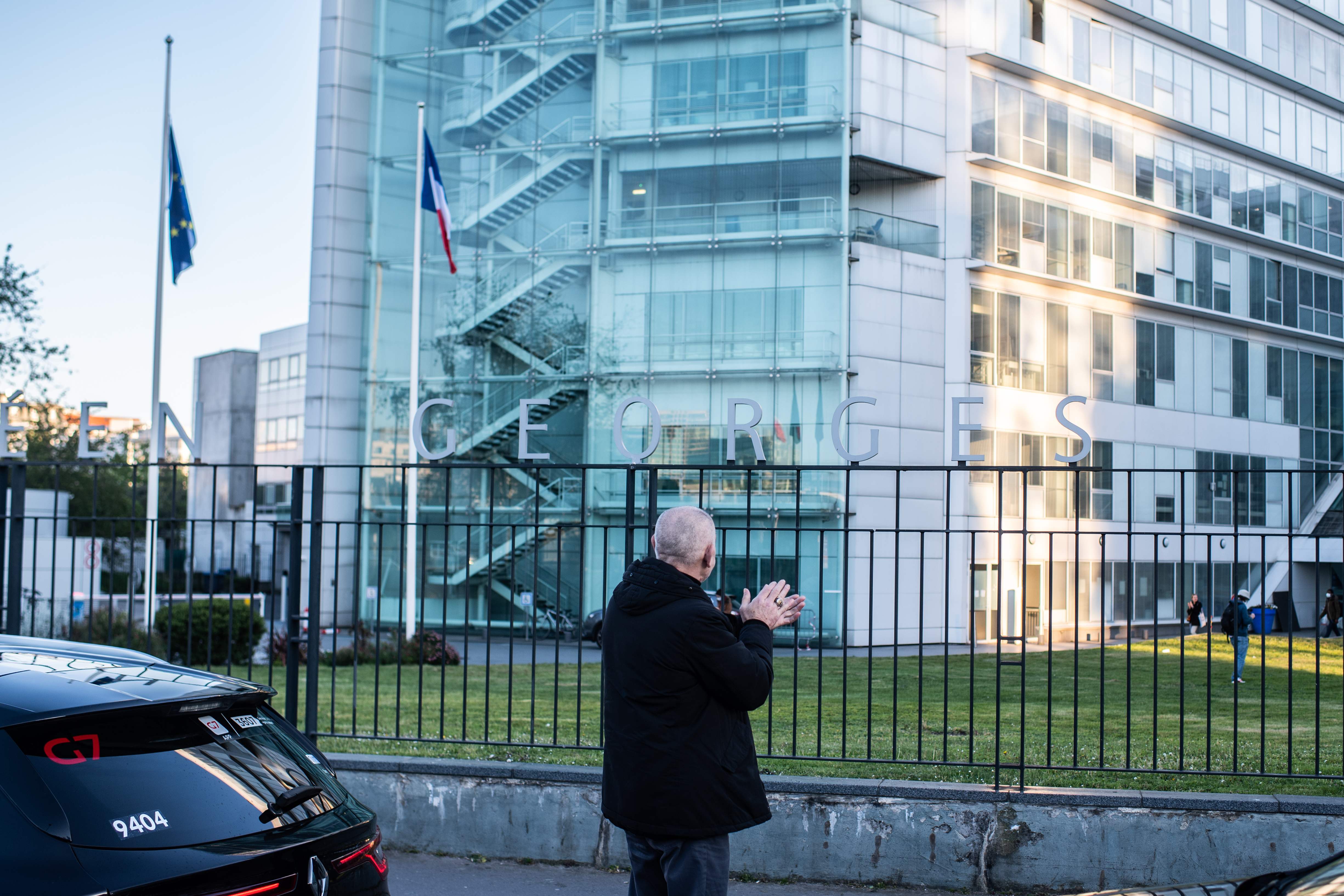 Seorang pria bertepuk tangan di depan RS Georges Pompidou, Paris, Prancis sebagai bentuk dukungan untuk tenaga medis.