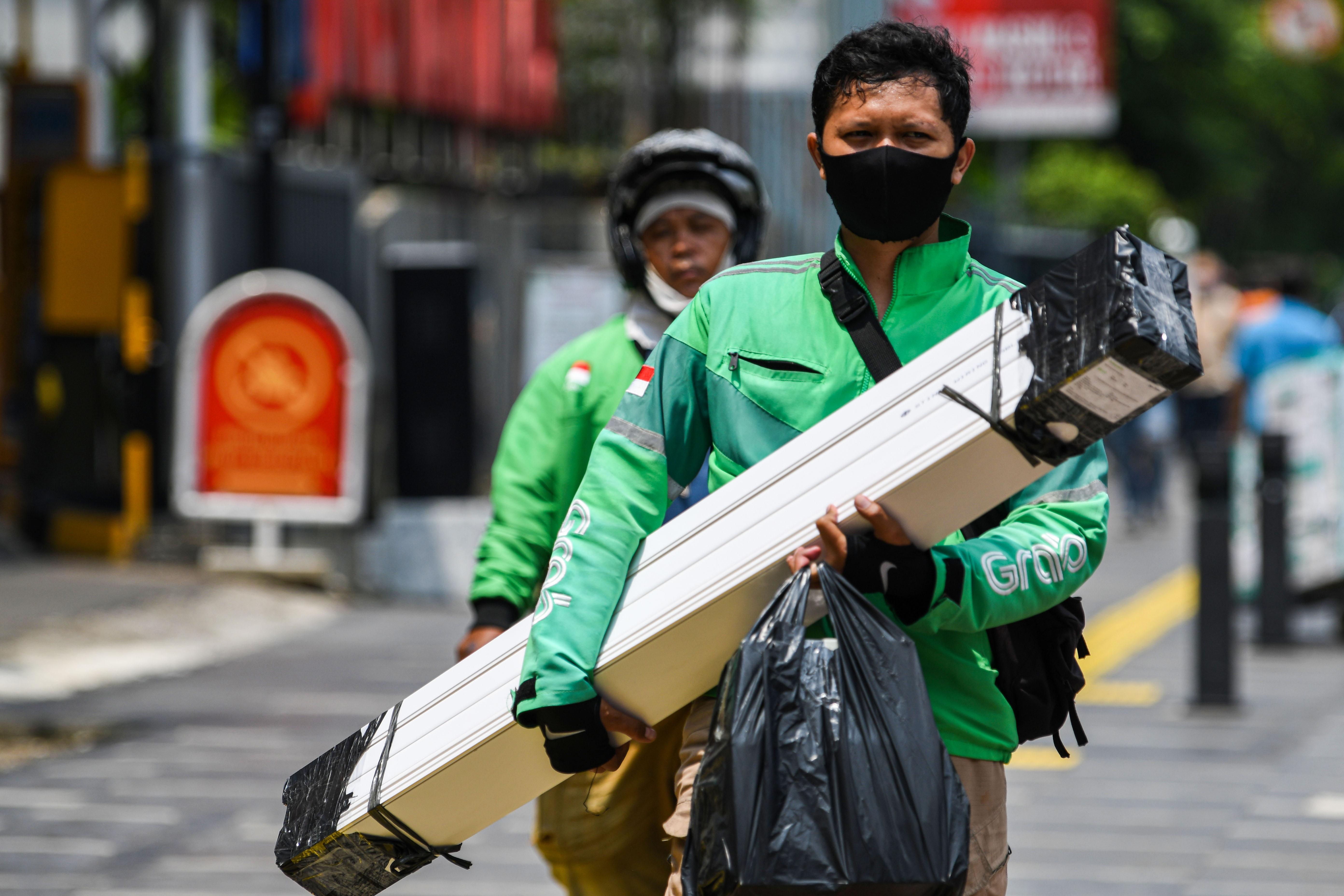 Pengemudi ojek daring membawa barang pesanan pelanggan di kawasan Kramat Raya, Jakarta.