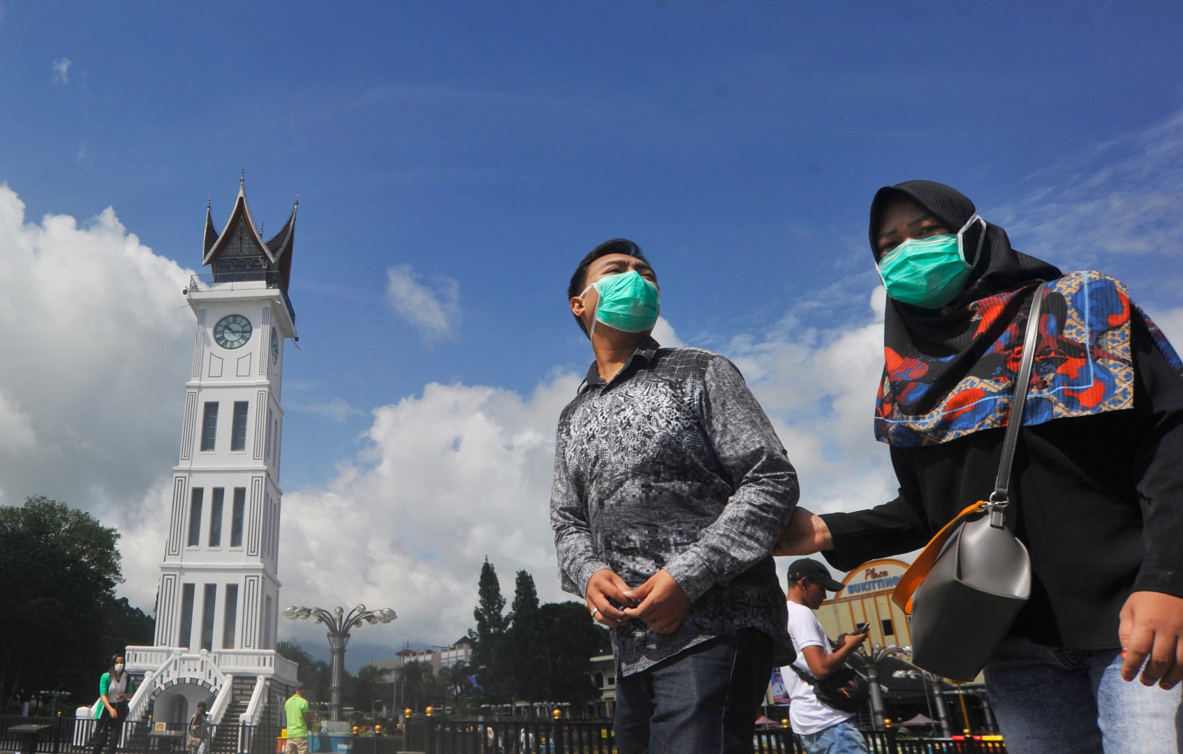 Pengunjung menggunakan masker melintas di depan Jam Gadang, Kota Bukittinggi, Sumatra Barat.