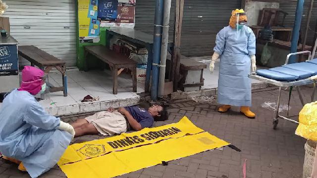 Petugas berbaju pelindung diri lengkap mengevakuasi seorang warga meninggal mendadak di Pasar Suko, Kabupaten Sidoarjo, Minggu (20/4/2020).