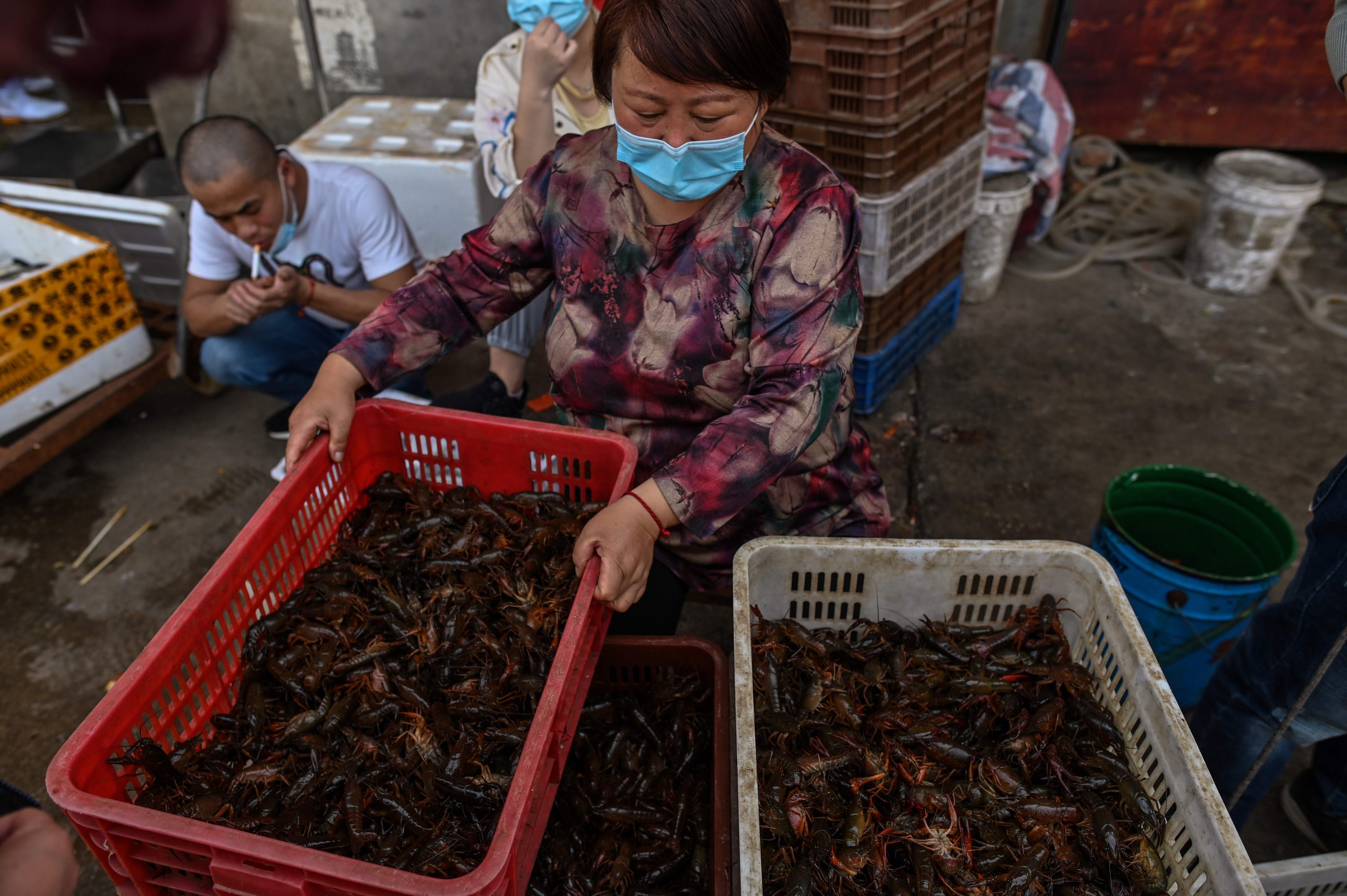Seorang wanita mengenakan daster menawarkan udang untuk dijual di Pasar Baishazhou Wuhan.