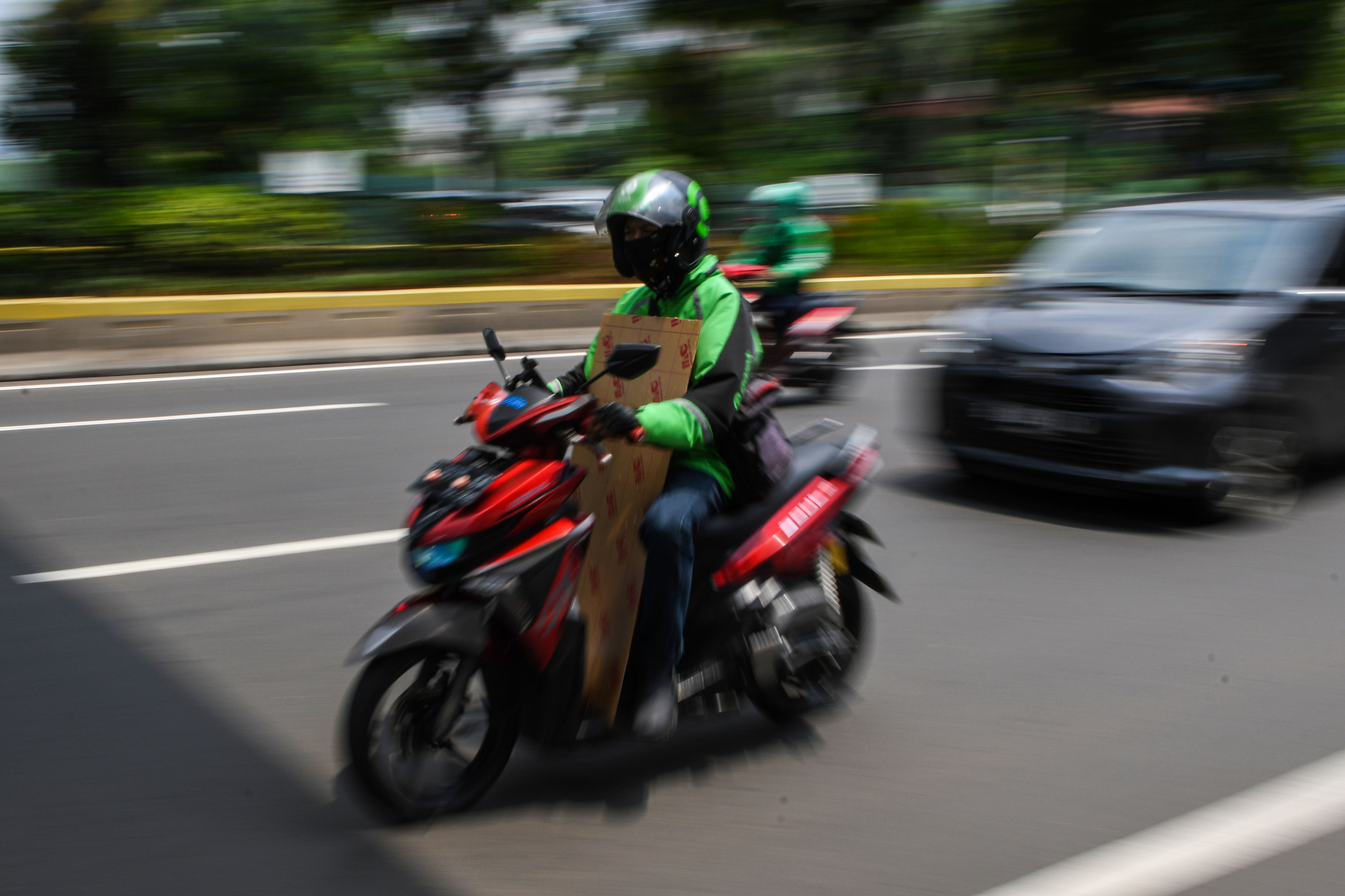 Pengemudi ojek daring membawa barang pesanan pelanggan saat melintas di kawasan Kramat Raya, Jakarta, Senin (13/4).