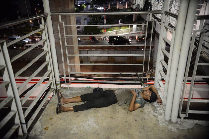 Penyandang Masalah dan Kesejahteraan Sosial (PMKS) beristirahat di jembatan penyeberangan orang di kawasan Rasuna Said, Jakarta.