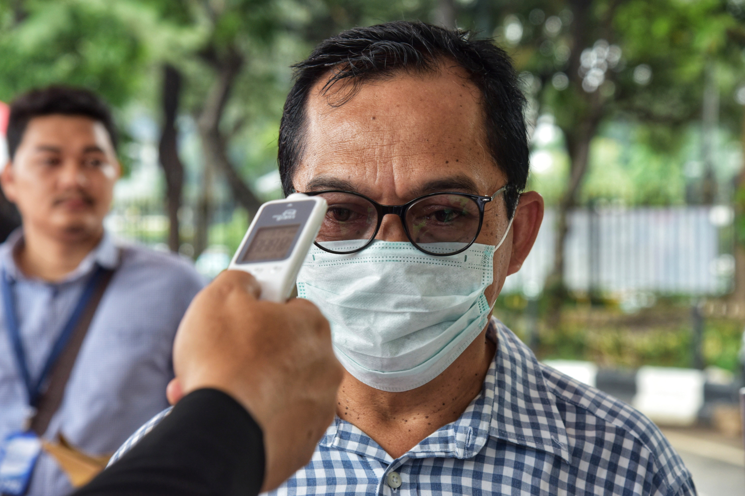 Selama pandemi virus korona, petugas wajib mengecek suhu tubuh saat di pintu masuk.