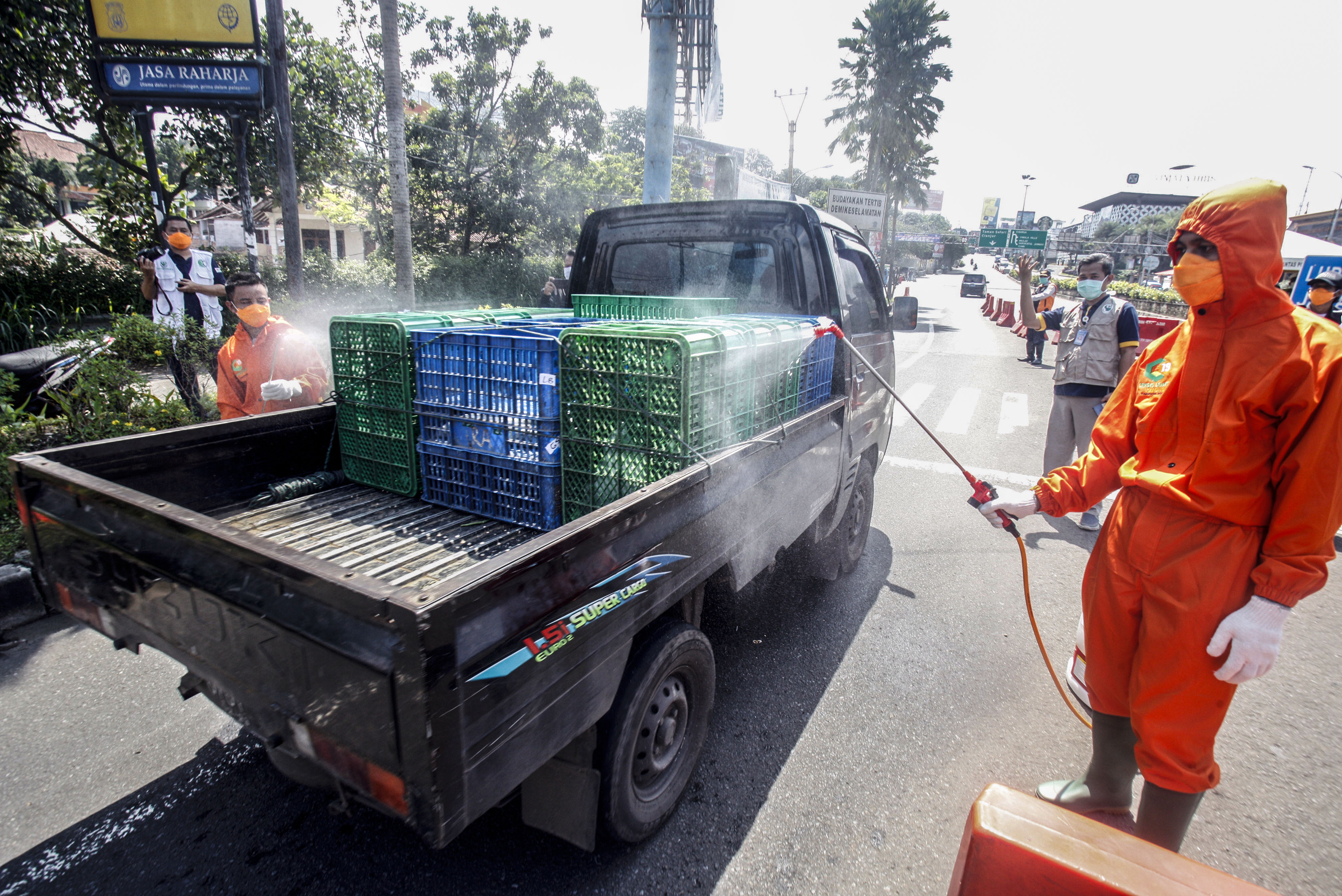 Petugas Dinas Kesehatan Kabupaten Bogor menyemprotkan cairan disinfektan ke mobil yang melintas di jalur wisata Puncak.