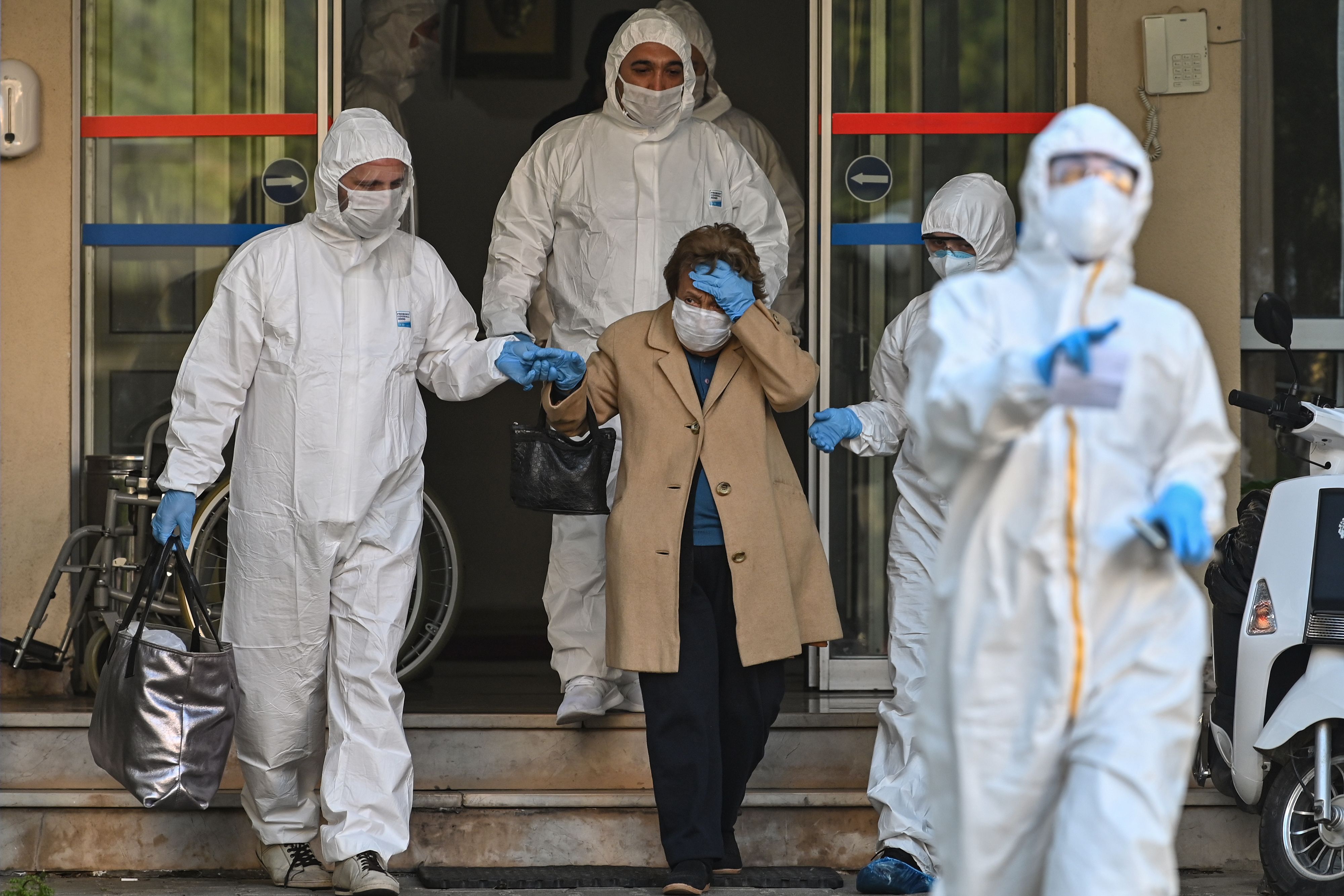 Paramedis Turki yang mengenakan pakaian pelindung membantu pasien yang menunjukkan gejala covid-19 ke ambulans.