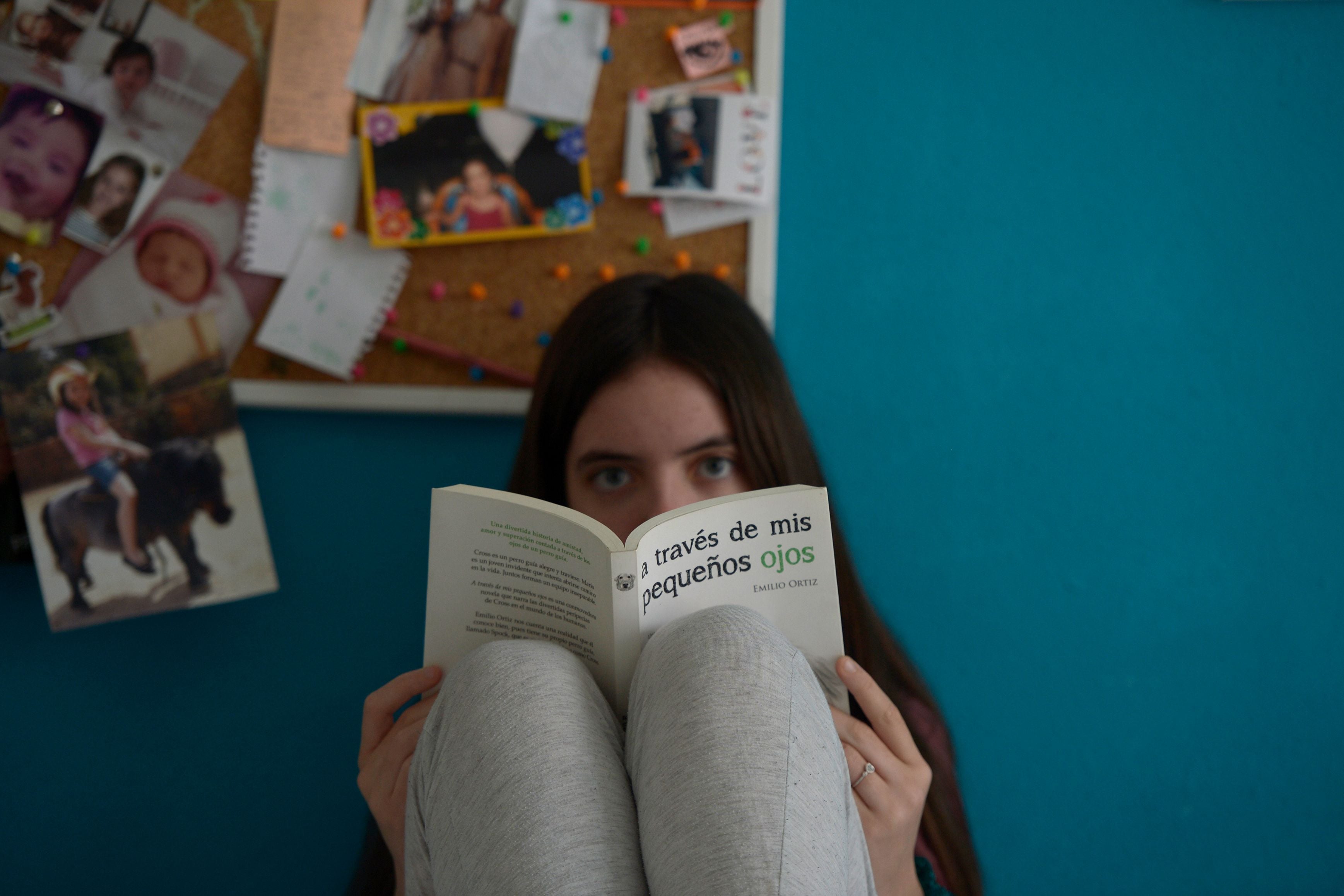 Seorang anak perempuan membaca saat menjalankan aturan di rumah saja di Seville, Spanyol.