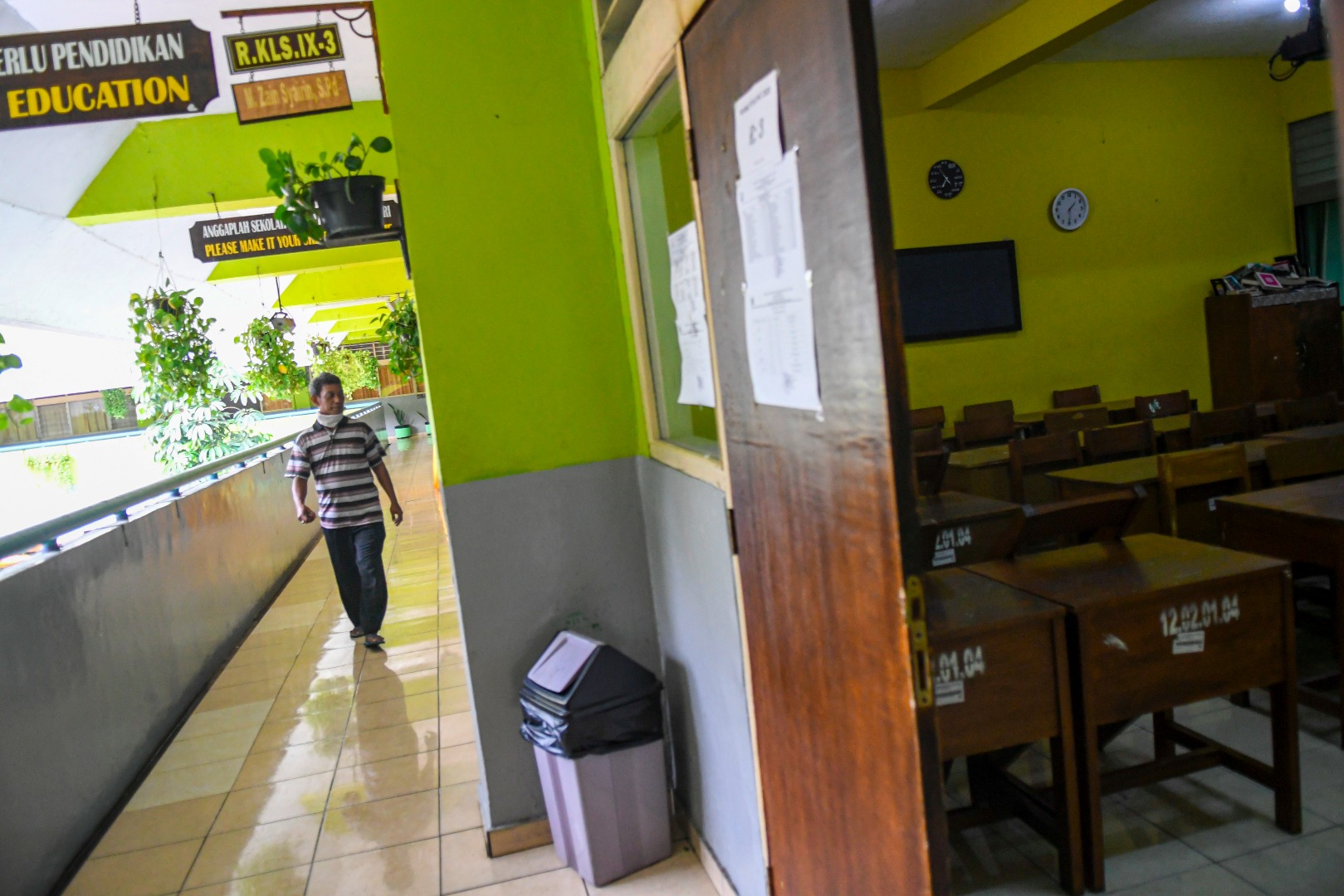 Petugas berjalan didepan ruang kelas SMP 216 Jakarta Pusat, saat sekolah diliburkan untuk mencegah penyebaran covid-19.
