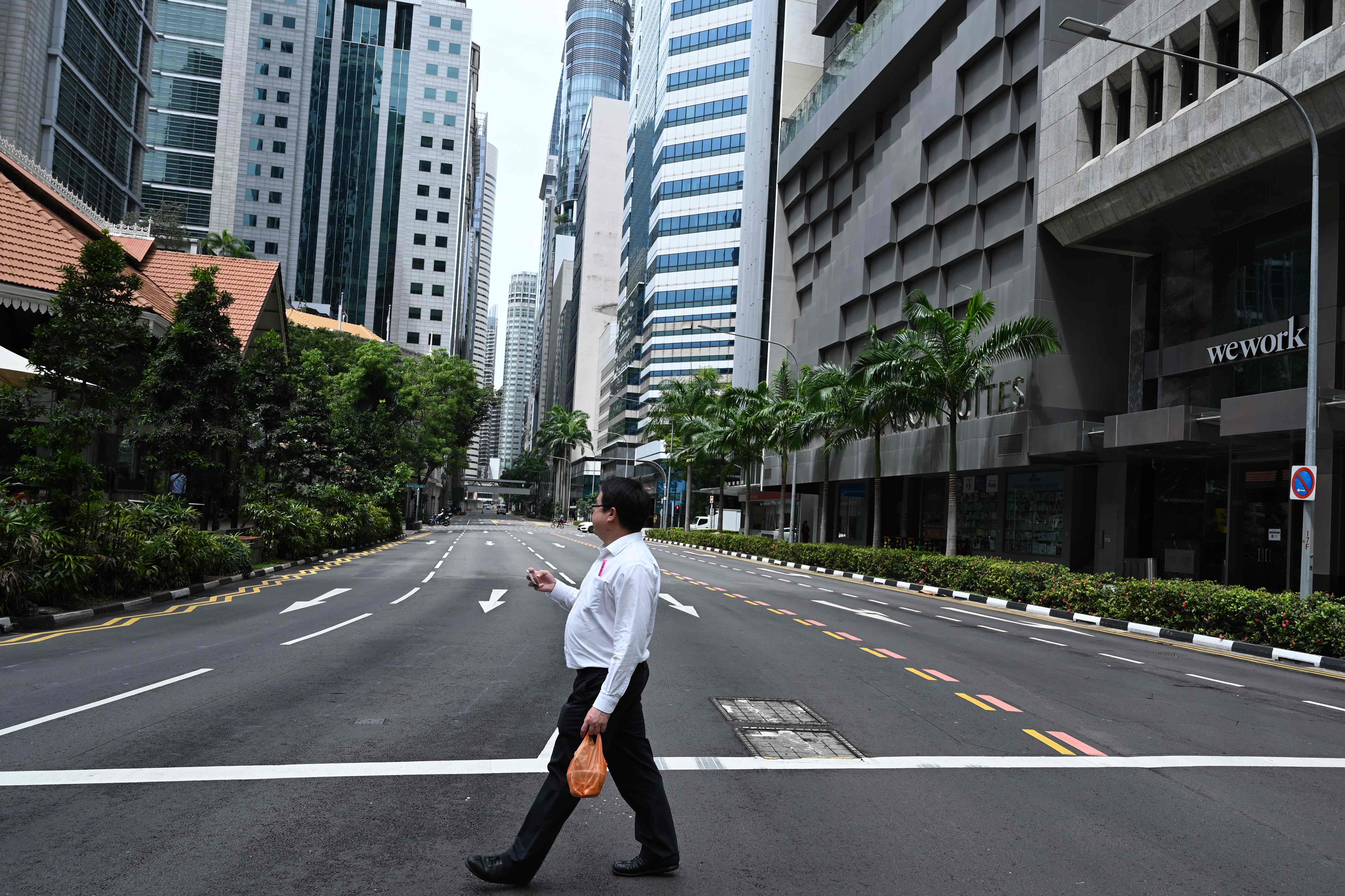 Warga menyeberang jalan di Kota Singapura yang kosong.