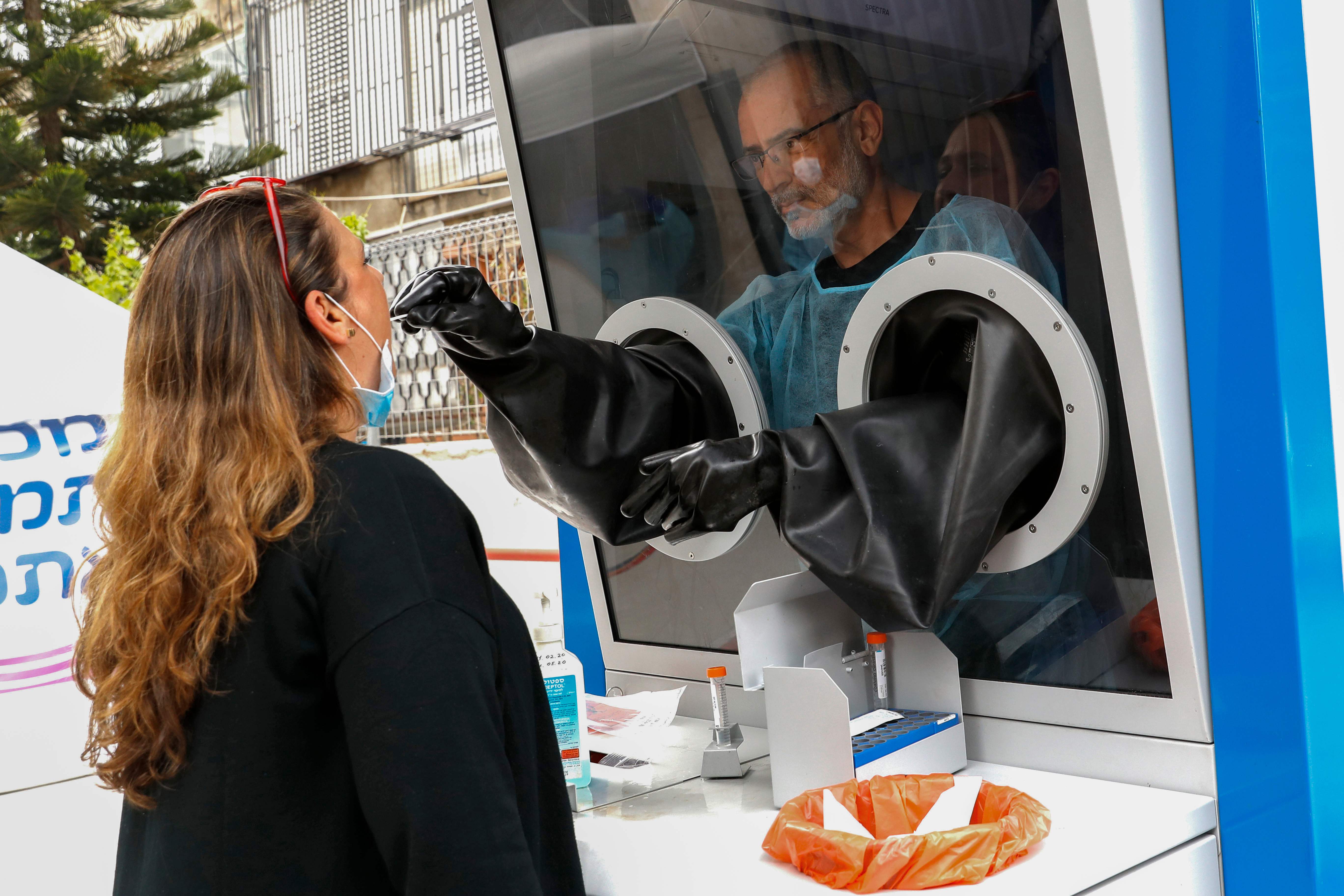 Warga menjalani test swab covid-19 di booth pemeriksaan yang didirikan di Tel Aviv, Israel.